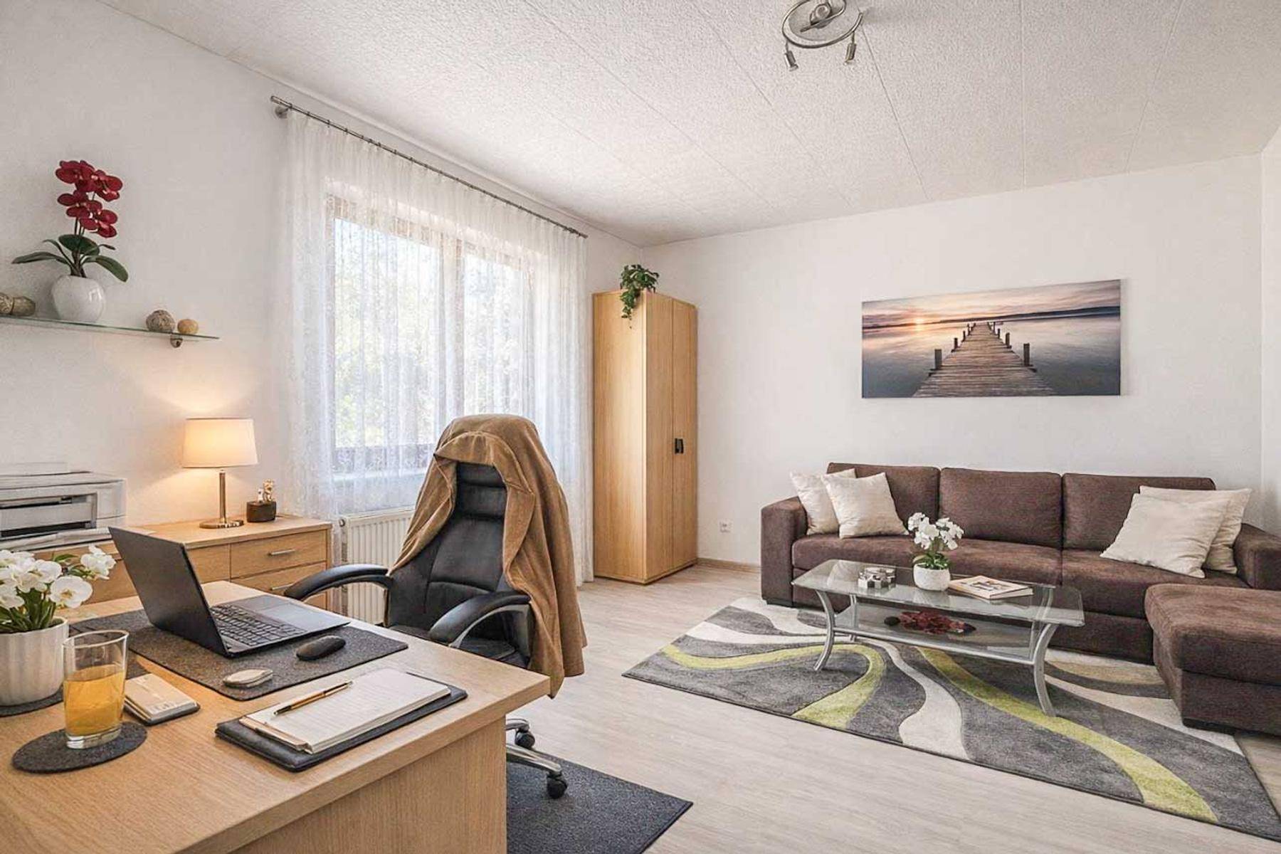 Helles Arbeitszimmer mit Schreibtisch, Sofa und großem Fenster.