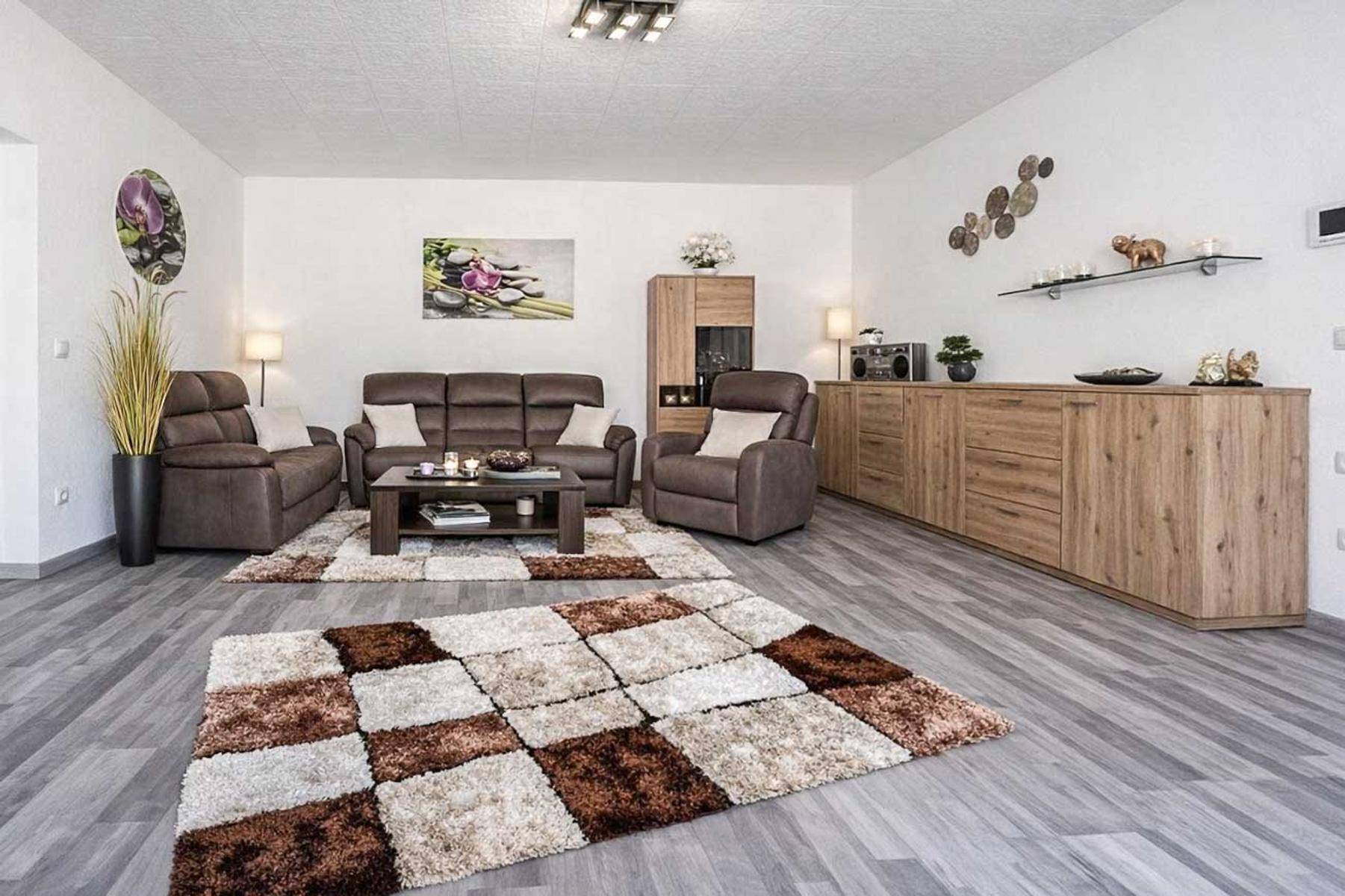 Geräumiges Wohnzimmer mit bequemen Sofas, Holzmöbeln und gemustertem Teppich.