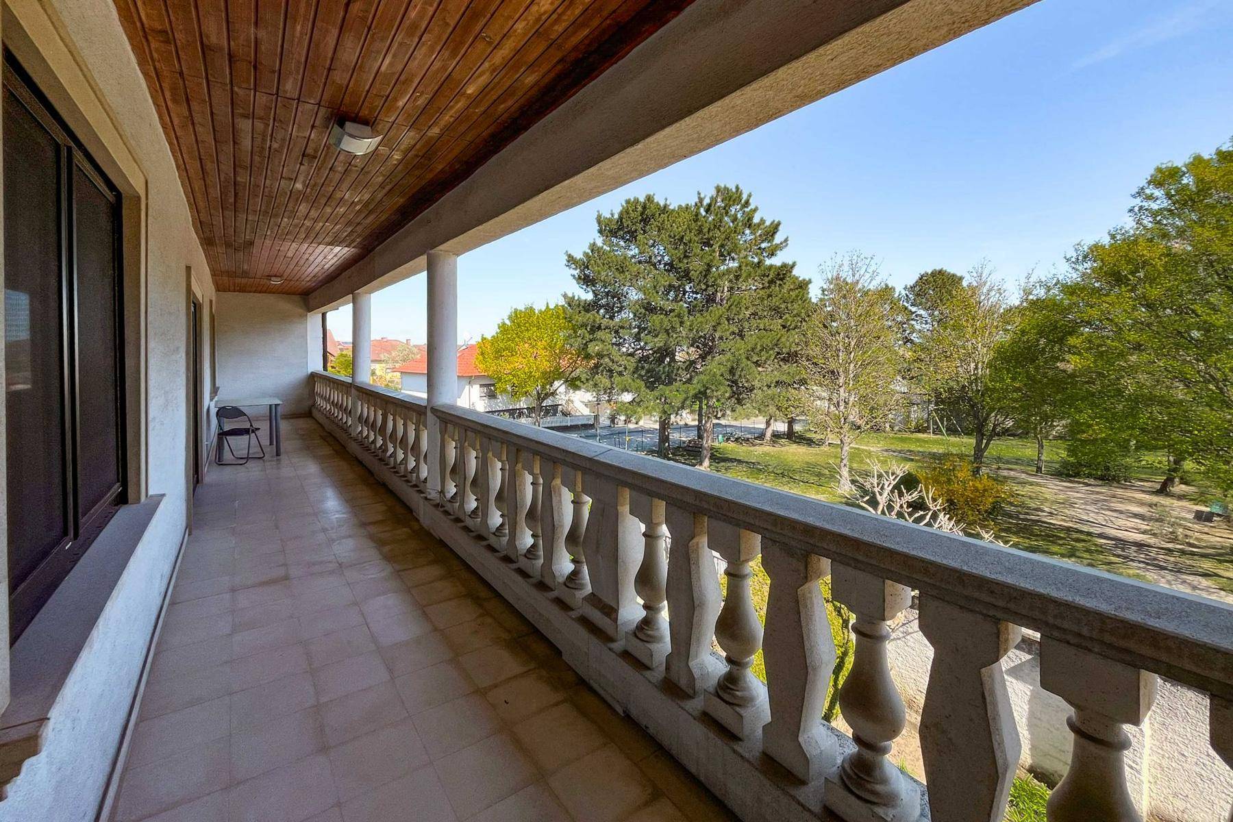 Langer überdachter Balkon mit Balustrade und Blick ins Grüne.