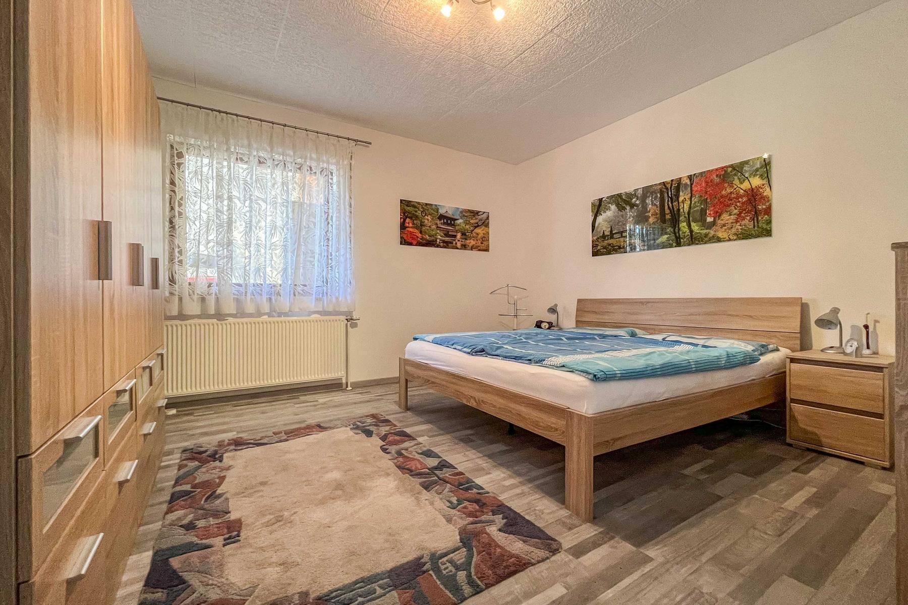 Gemütliches Schlafzimmer mit Holzbett, großem Kleiderschrank und Fenster.