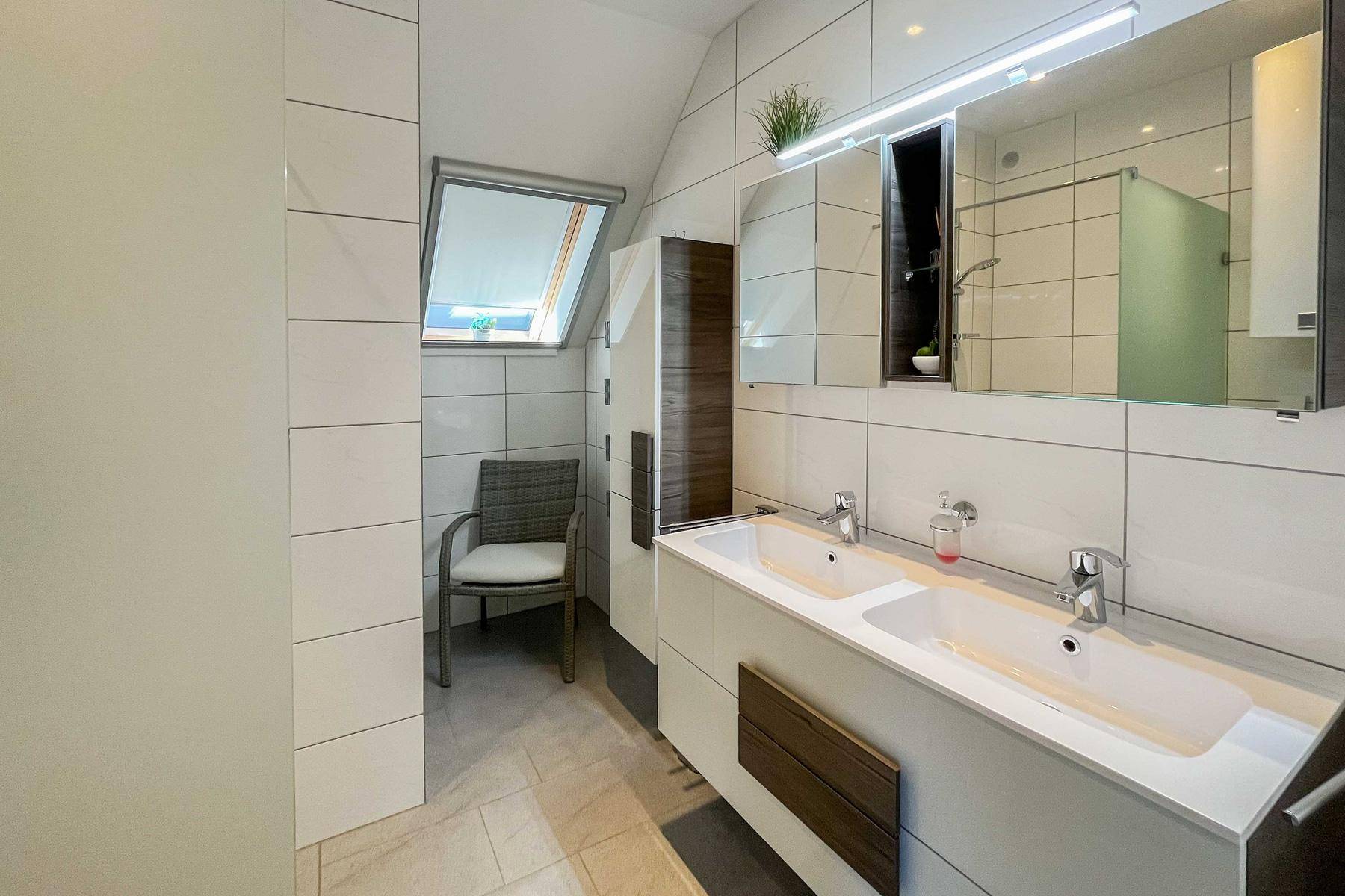 Modernes Badezimmer mit Doppelwaschbecken, großer Dusche und Dachfenster.