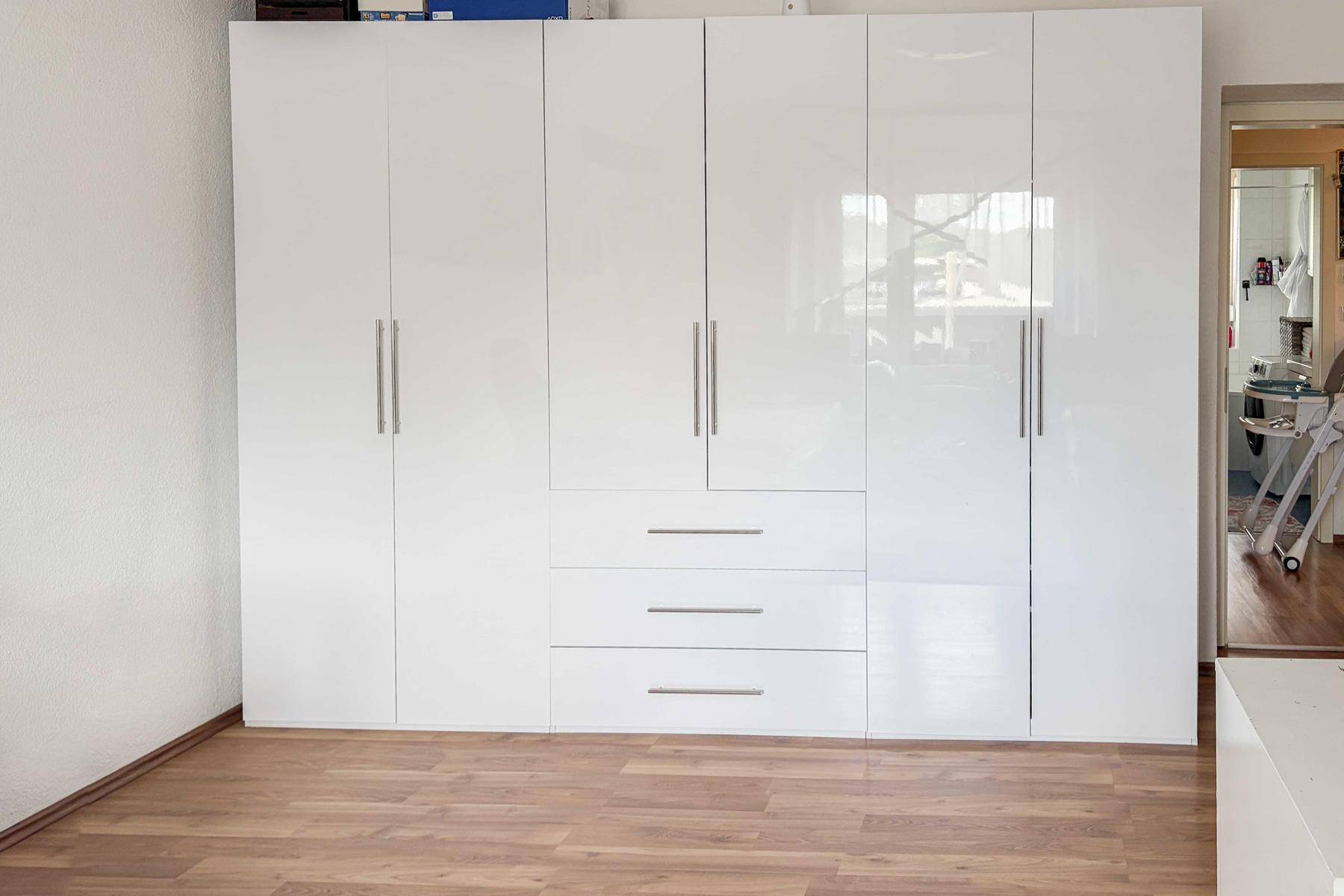 Schlafzimmer mit einem großen, modernen, weißen Einbauschrank und Laminatboden.