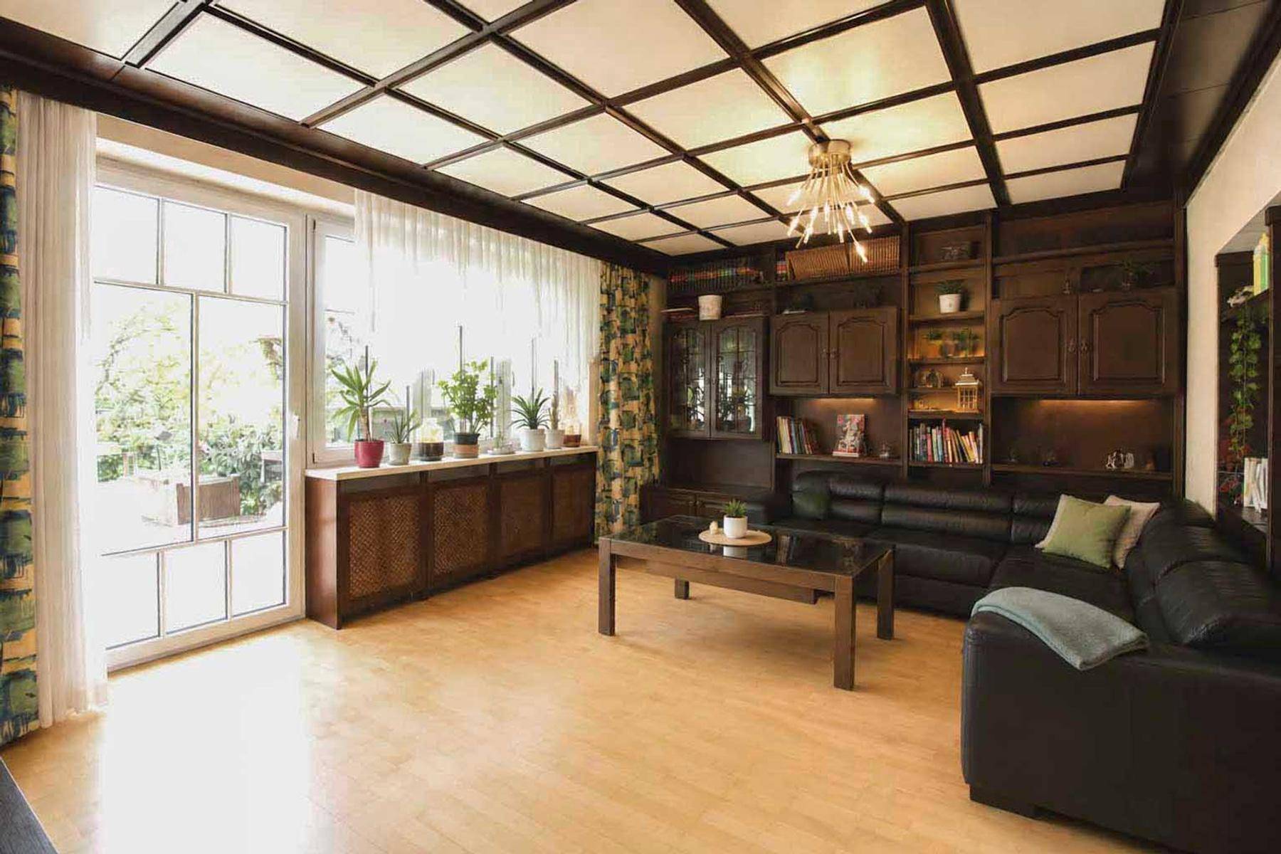Geräumiges Wohnzimmer mit Holzbalkendecke, Parkettboden und großem Fenster zum Garten.