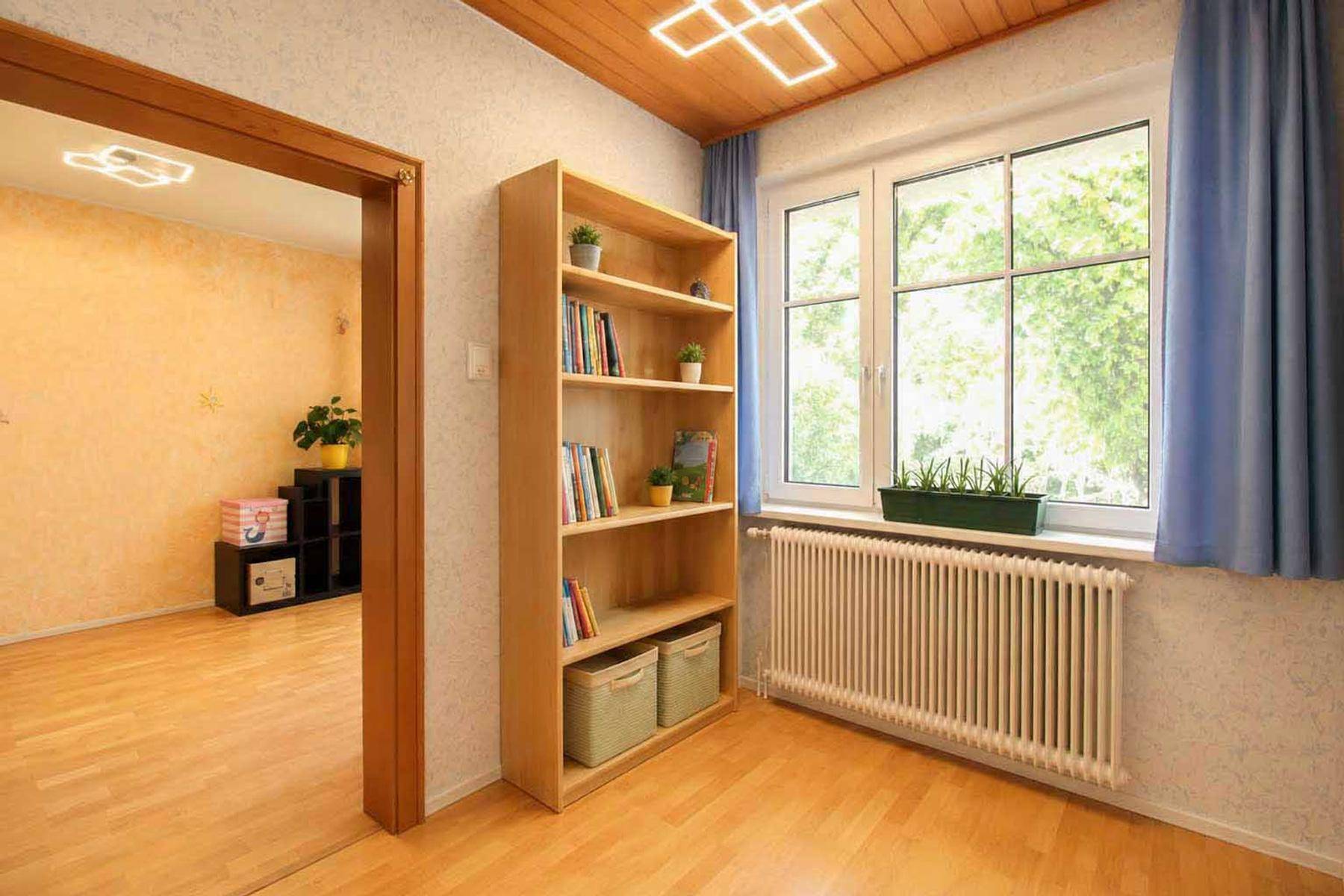 Heller Flur mit Holzdecke, Parkettboden und einem Bücherregal.