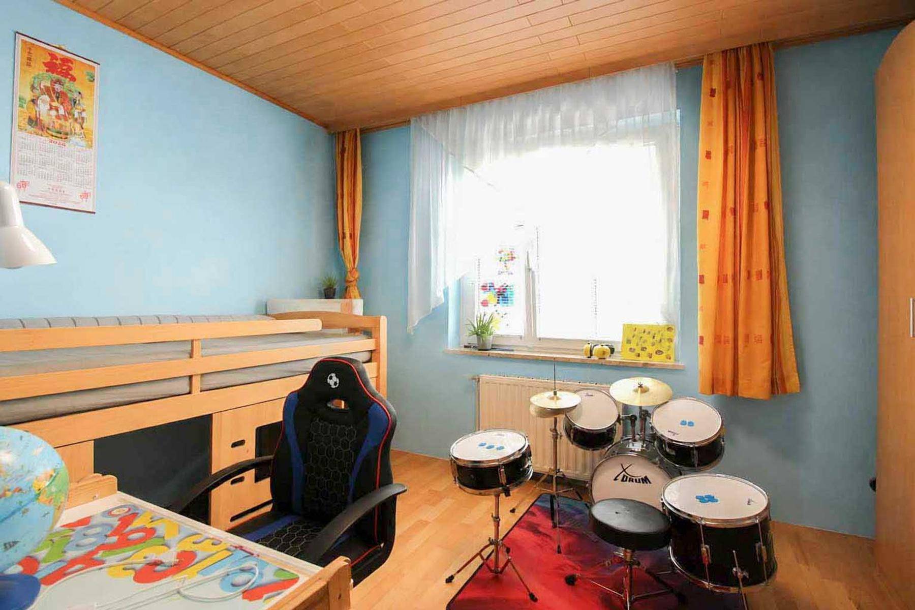 Buntes Kinderzimmer mit Hochbett, Schlagzeug und Holzdecke.