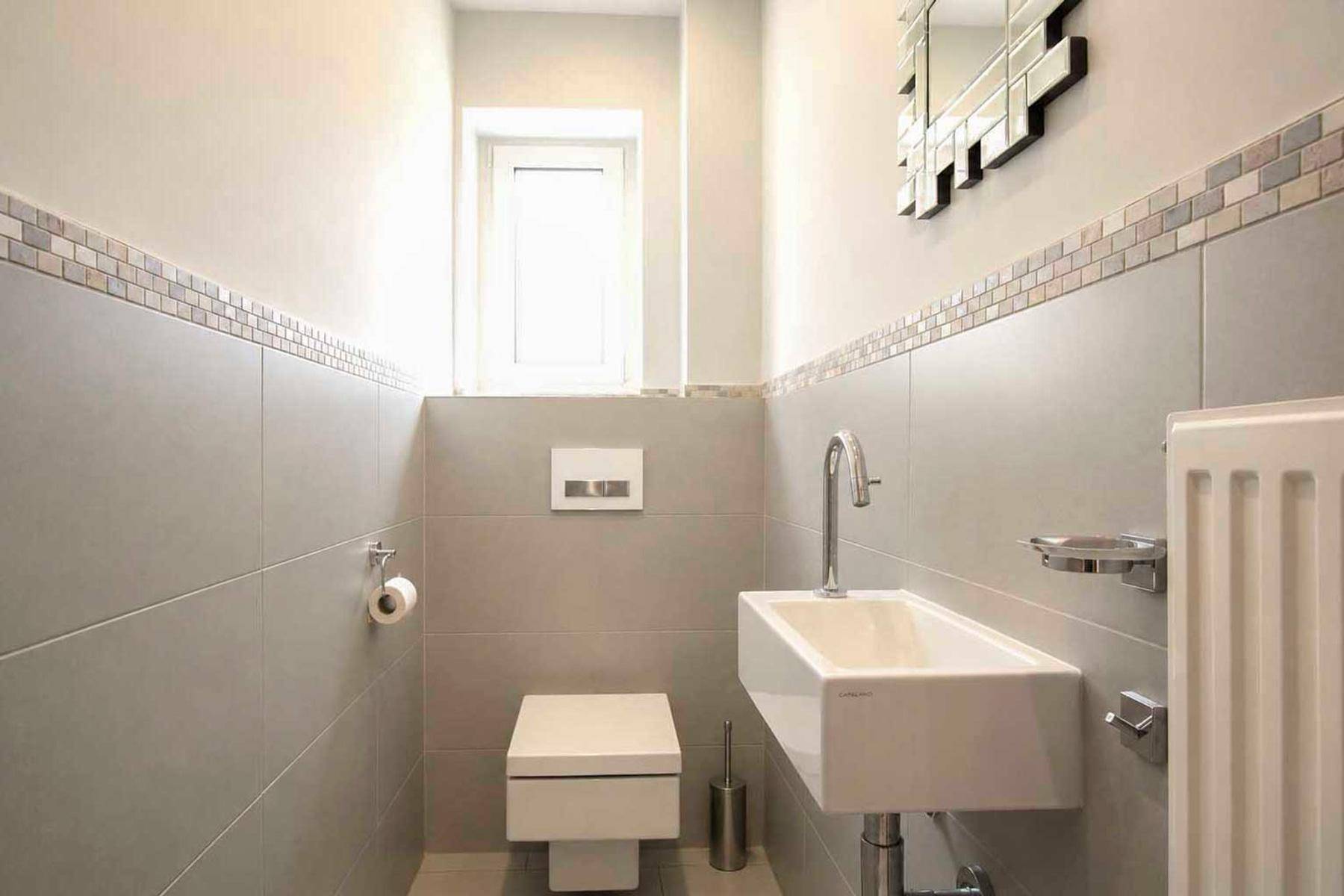 Modernes Gäste-WC mit wandhängendem WC, kleinem Waschbecken und Fenster.