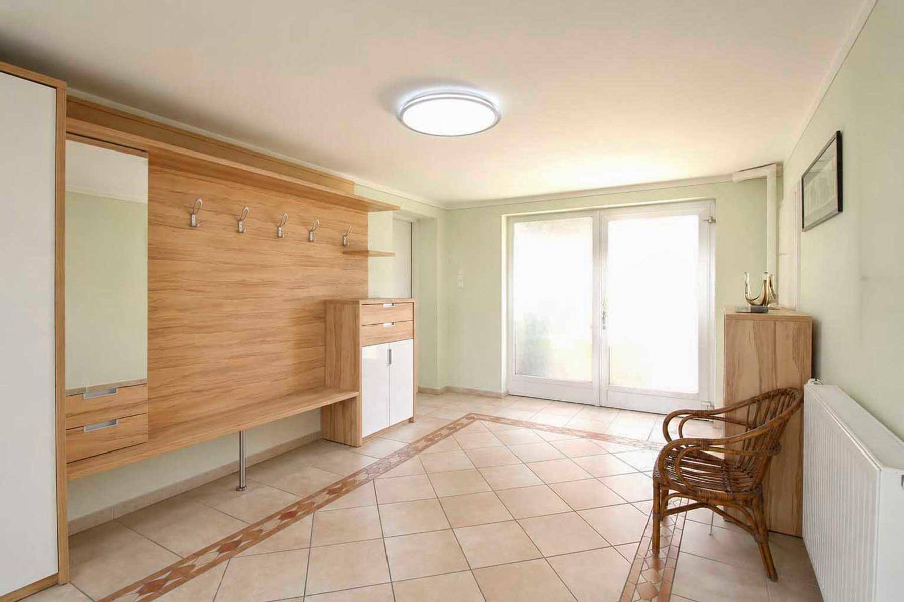Heller Eingangsbereich mit Garderobe, Fliesenboden und Zugang zum Garten.