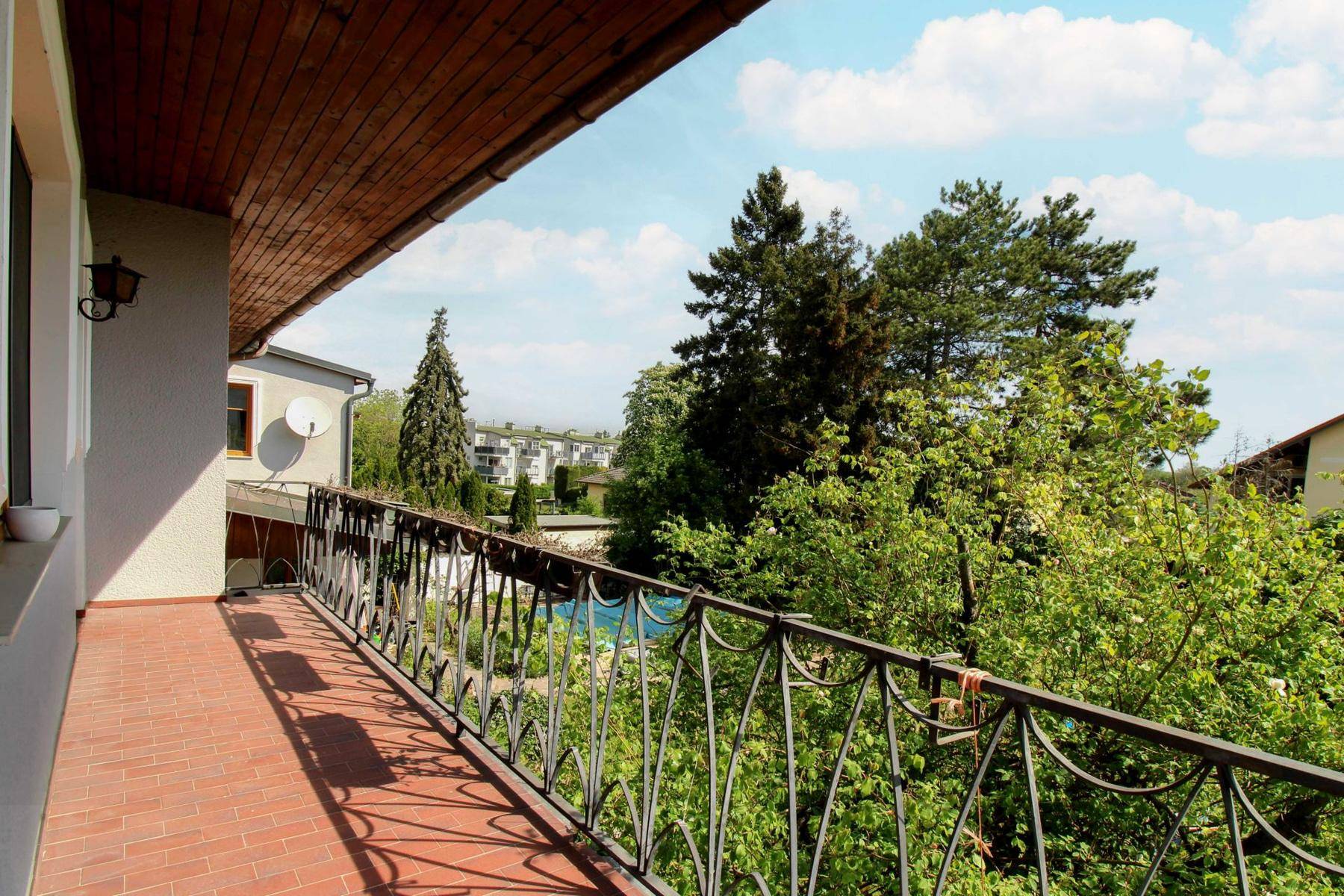 Langer Balkon mit schmiedeeisernem Geländer und Blick ins Grüne.