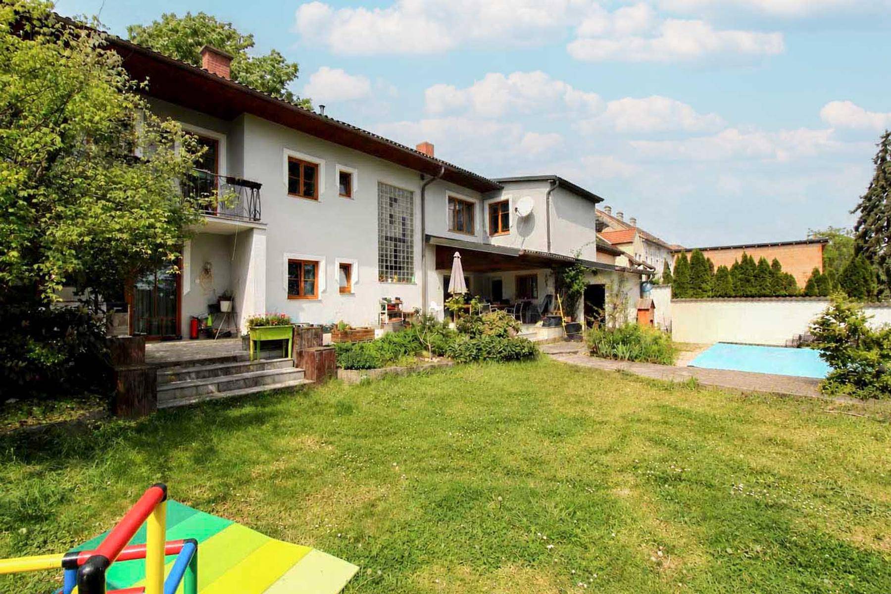 Großer Garten mit Rasen, Terrasse und einem kleinen Poolbereich.