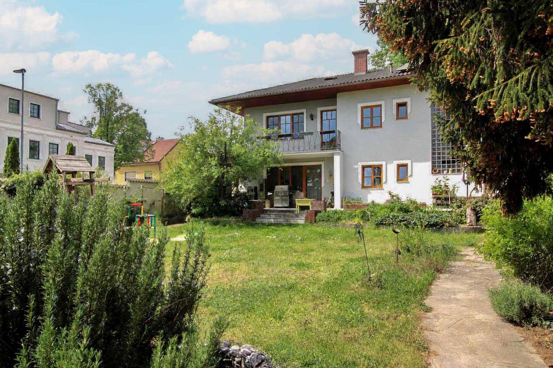 Weitläufiger Garten mit Rasenfläche, Spielplatz und Blick auf das Haus.