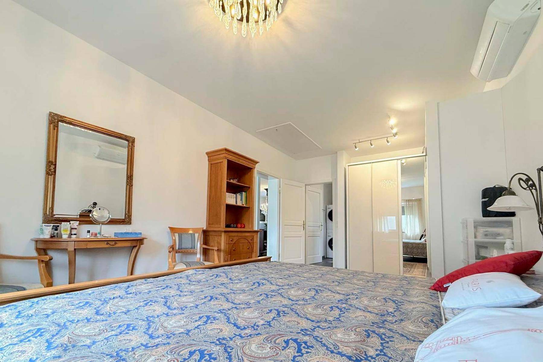 Schlafzimmer mit Schminktisch, Spiegel und Zugang zu weiteren Räumen.