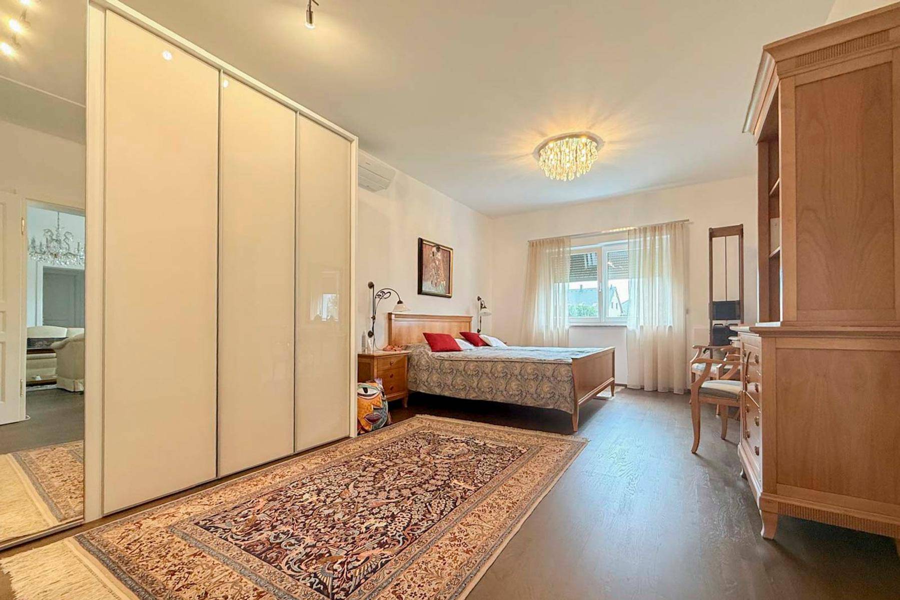 Schlafzimmer mit Doppelbett, Einbauschrank und Teppich auf Holzboden.