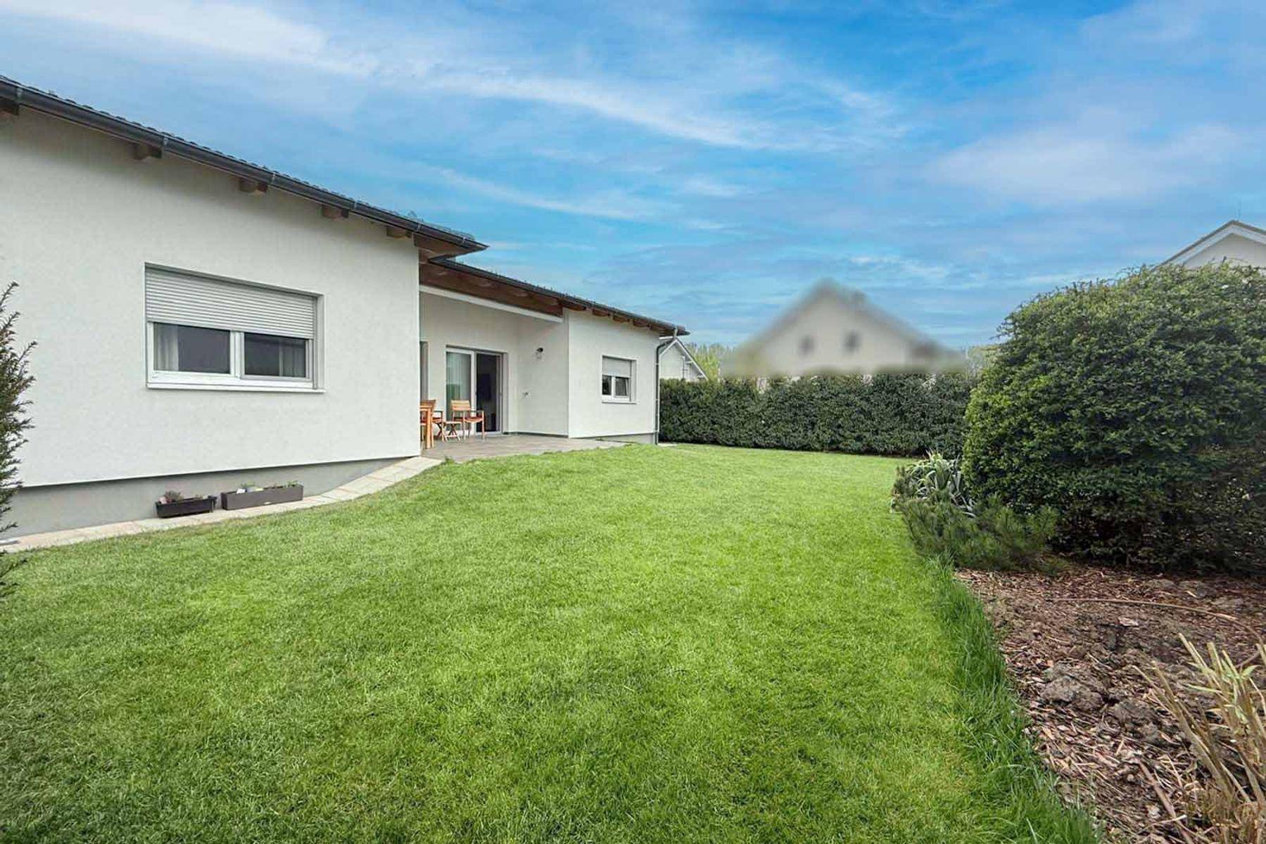 Rückseite des Hauses mit großem Rasenbereich und kleiner Terrasse.