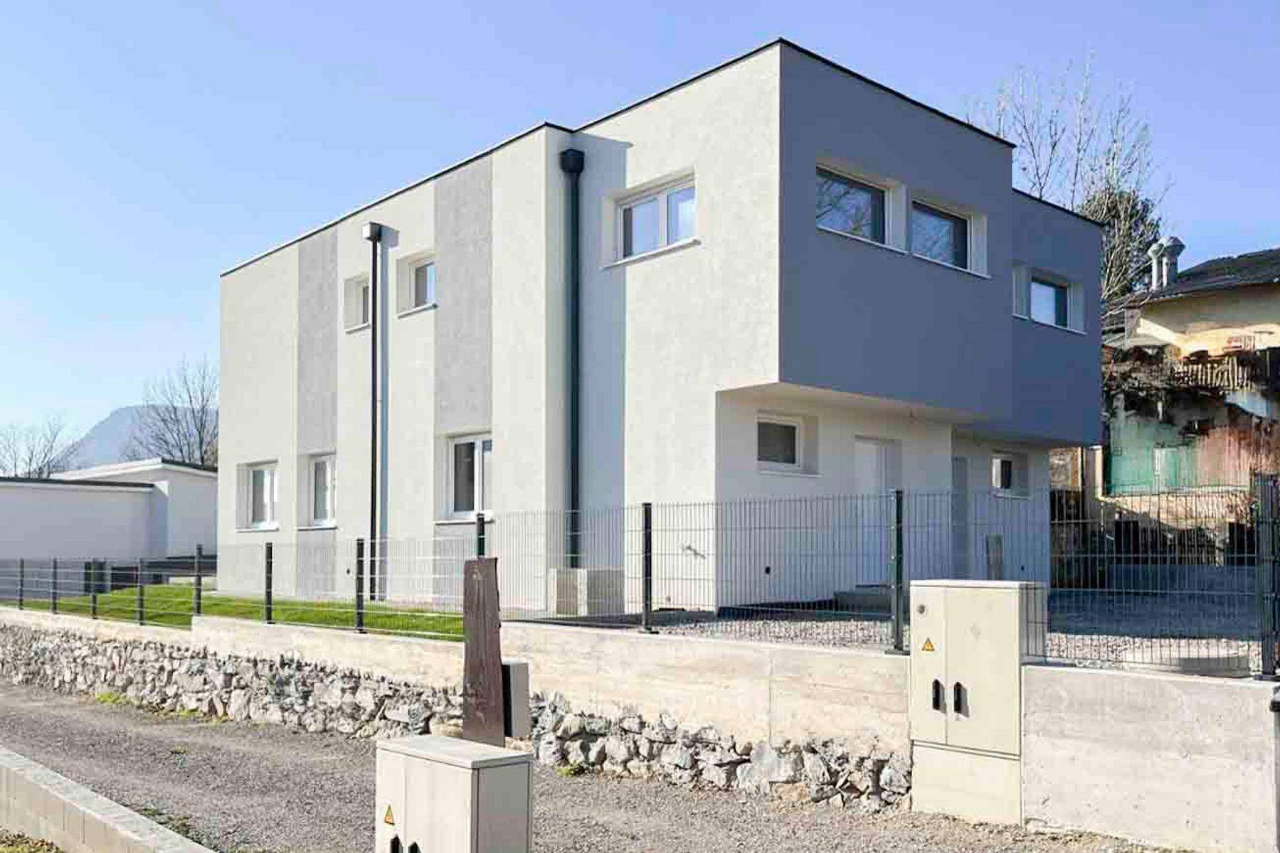 Moderne Architektur des Neubaus mit klaren Linien und einer Zufahrt im Vordergrund.