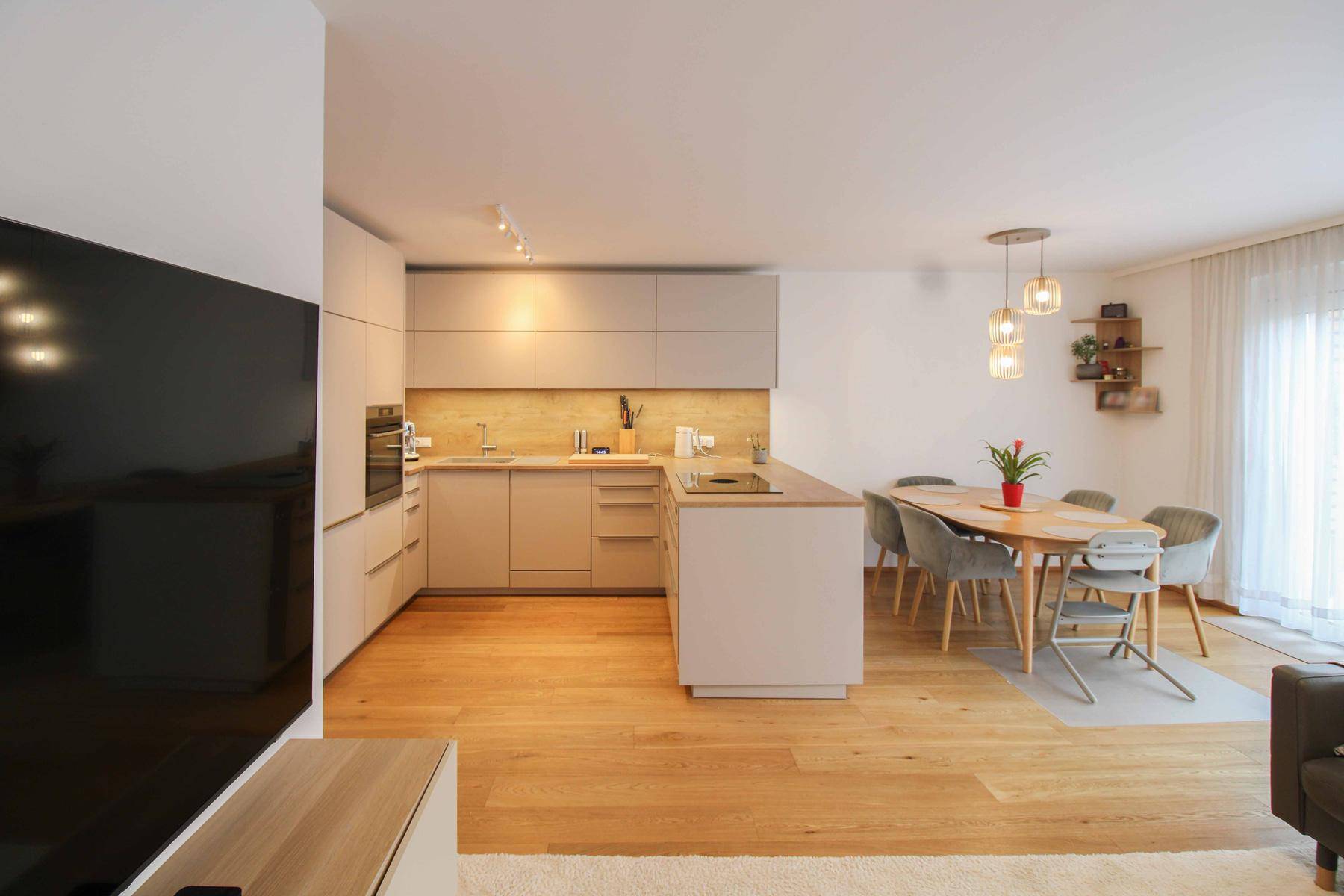 Moderne Einbauküche mit Kücheninsel und Essbereich in offenem Wohnkonzept.