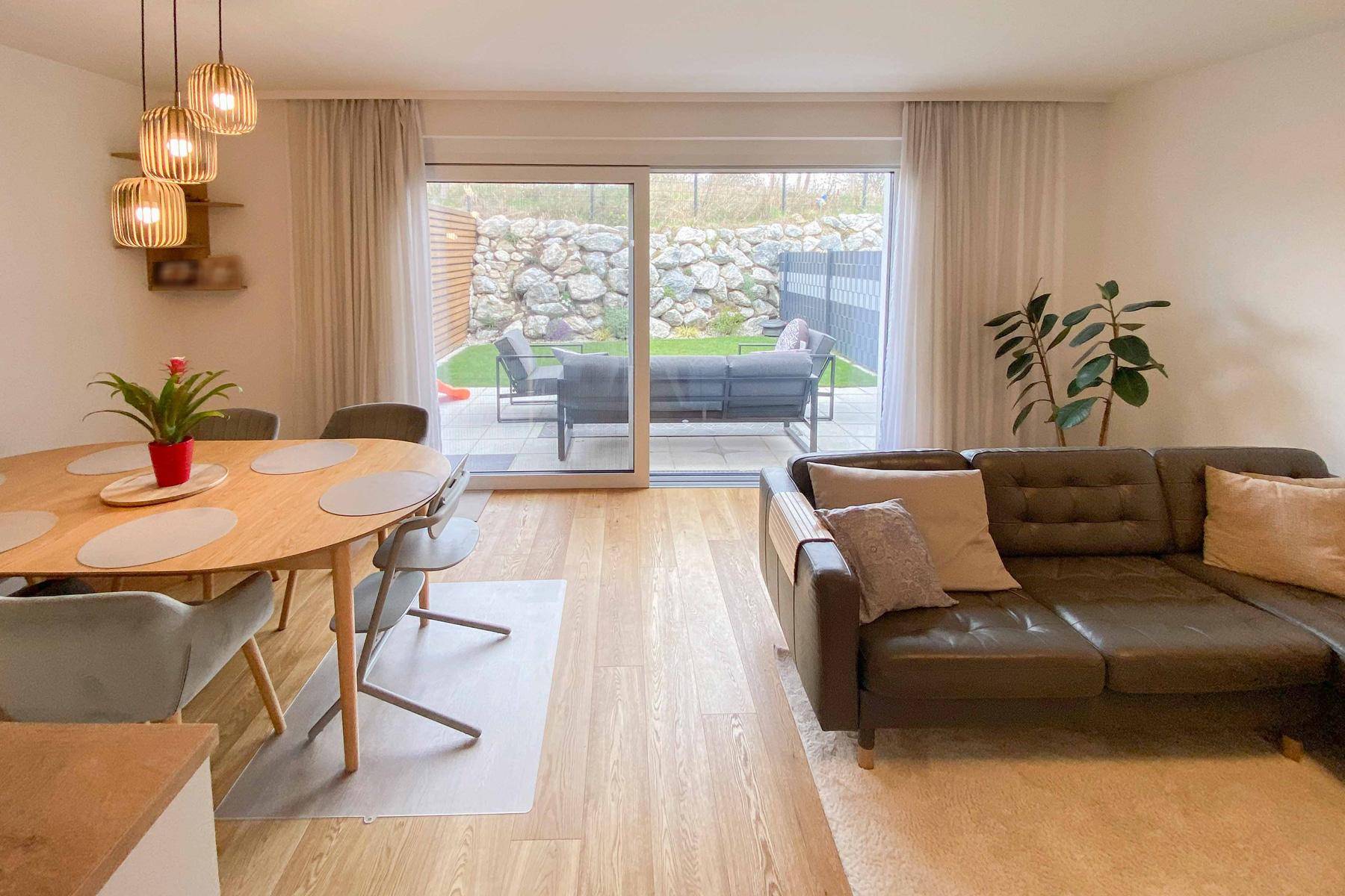 Gemütlicher Wohn-Essbereich mit Ledersofa und großem Schiebefenster zur Terrasse.