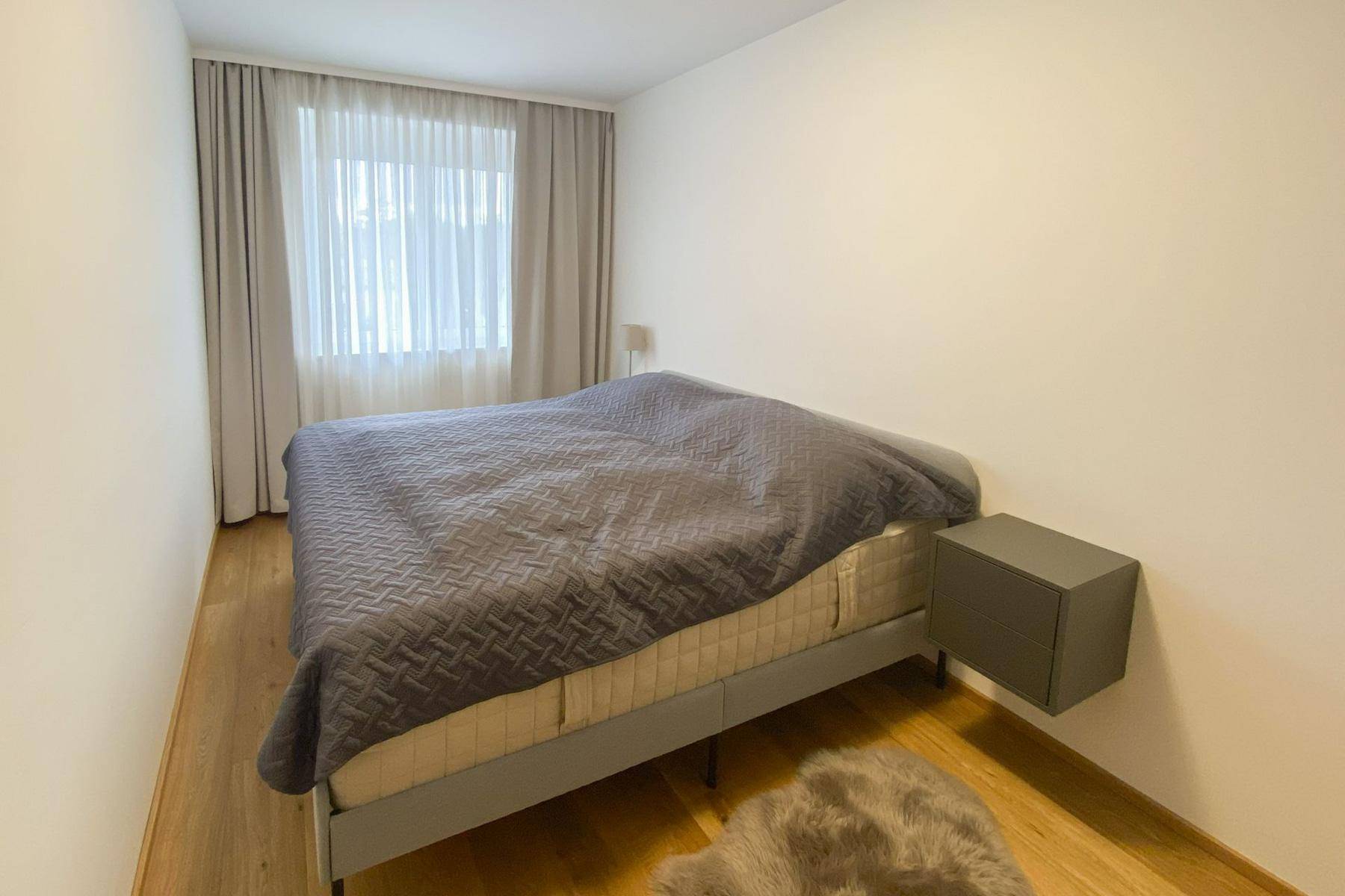 Ruhiges Schlafzimmer mit Doppelbett, schwebendem Nachttisch und Holzboden.