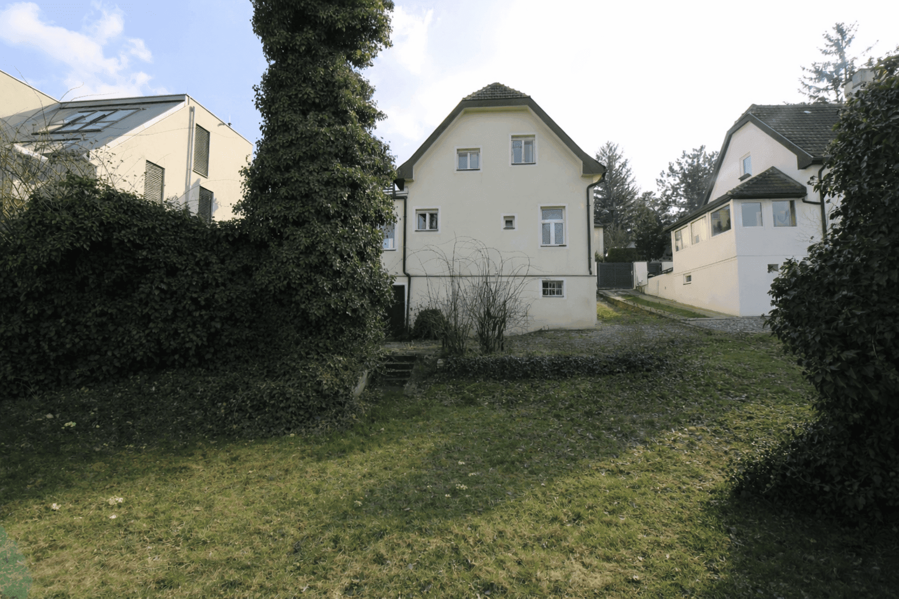 Rückansicht des Hauses mit großem Gartenbereich und umliegender Vegetation.