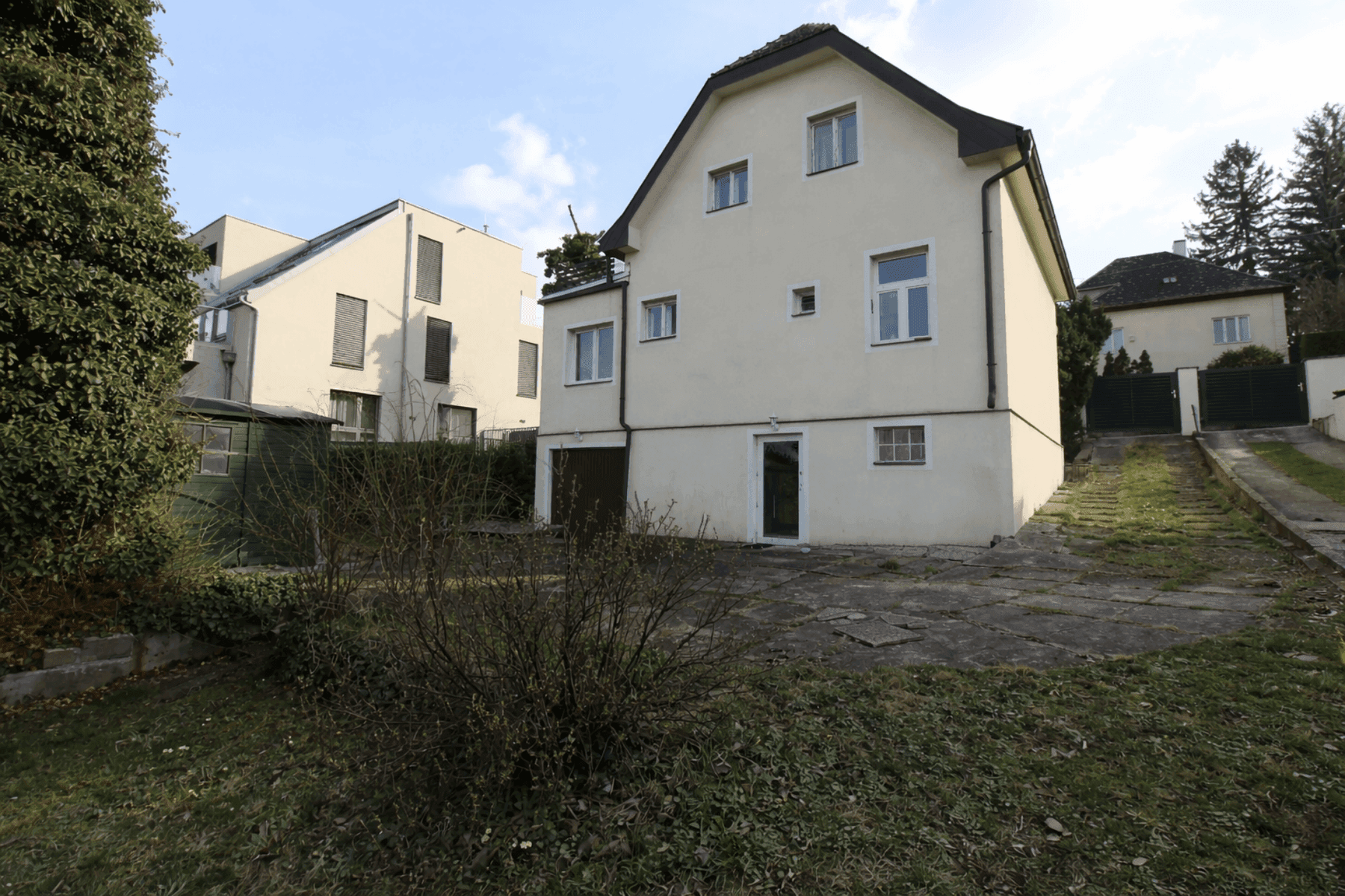 Seitenansicht des Hauses mit Zufahrt, Garage und weitläufigem Gartenbereich.