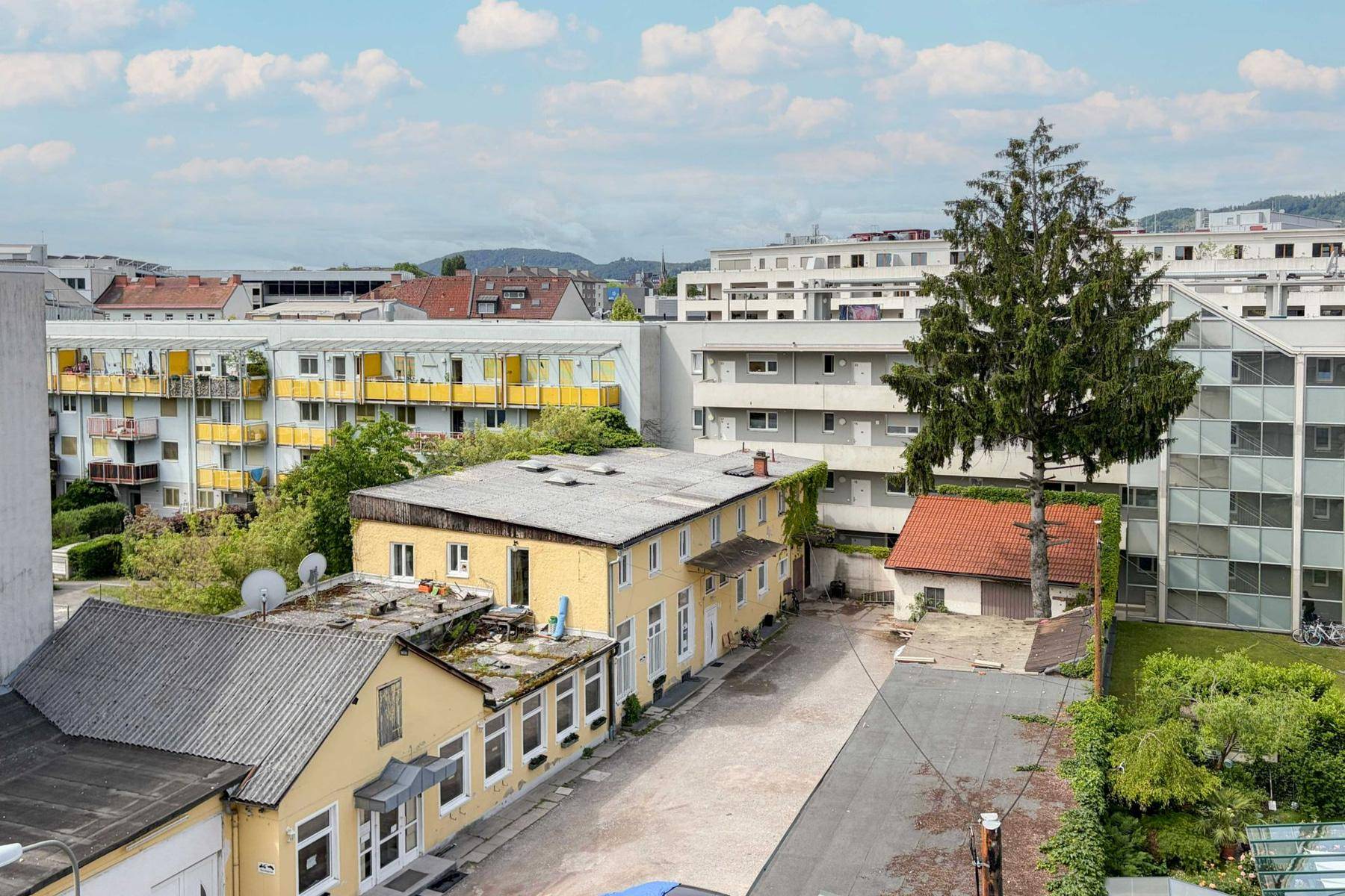 Weitläufige Ansicht von Wohngebäuden und Grünflächen unter einem bewölkten Himmel.