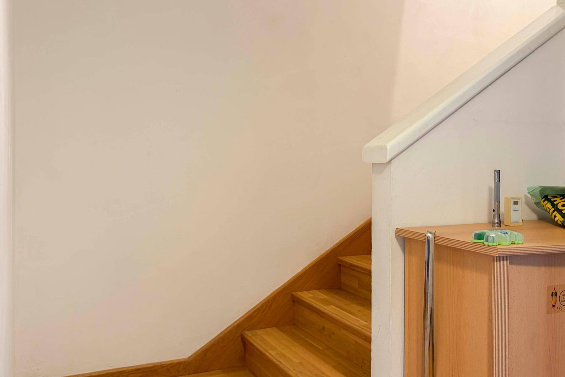 Holztreppe mit hellem Geländer und einem kleinen Schrank im Eingangsbereich.