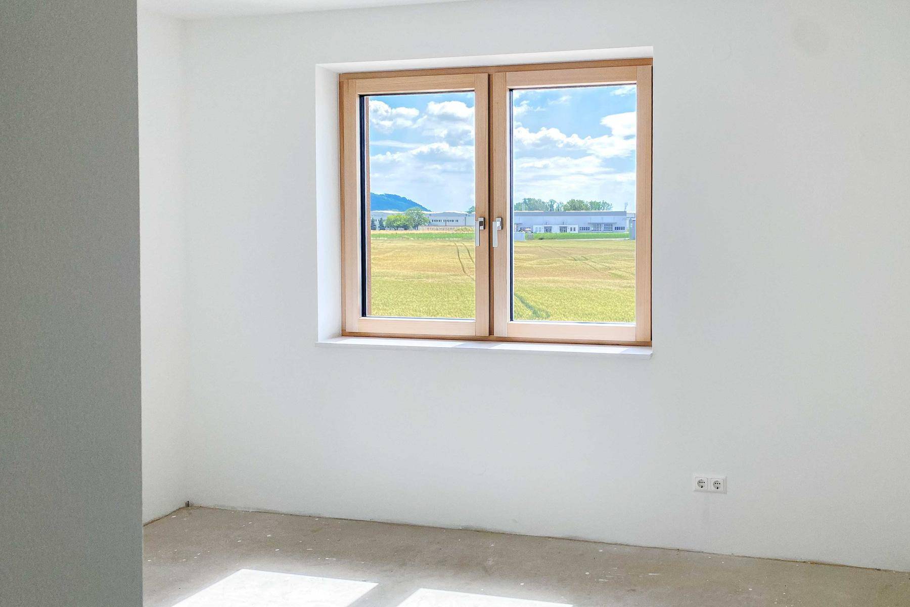 Fenster in einem hellen Raum mit weitem Blick über Felder und die Landschaft.