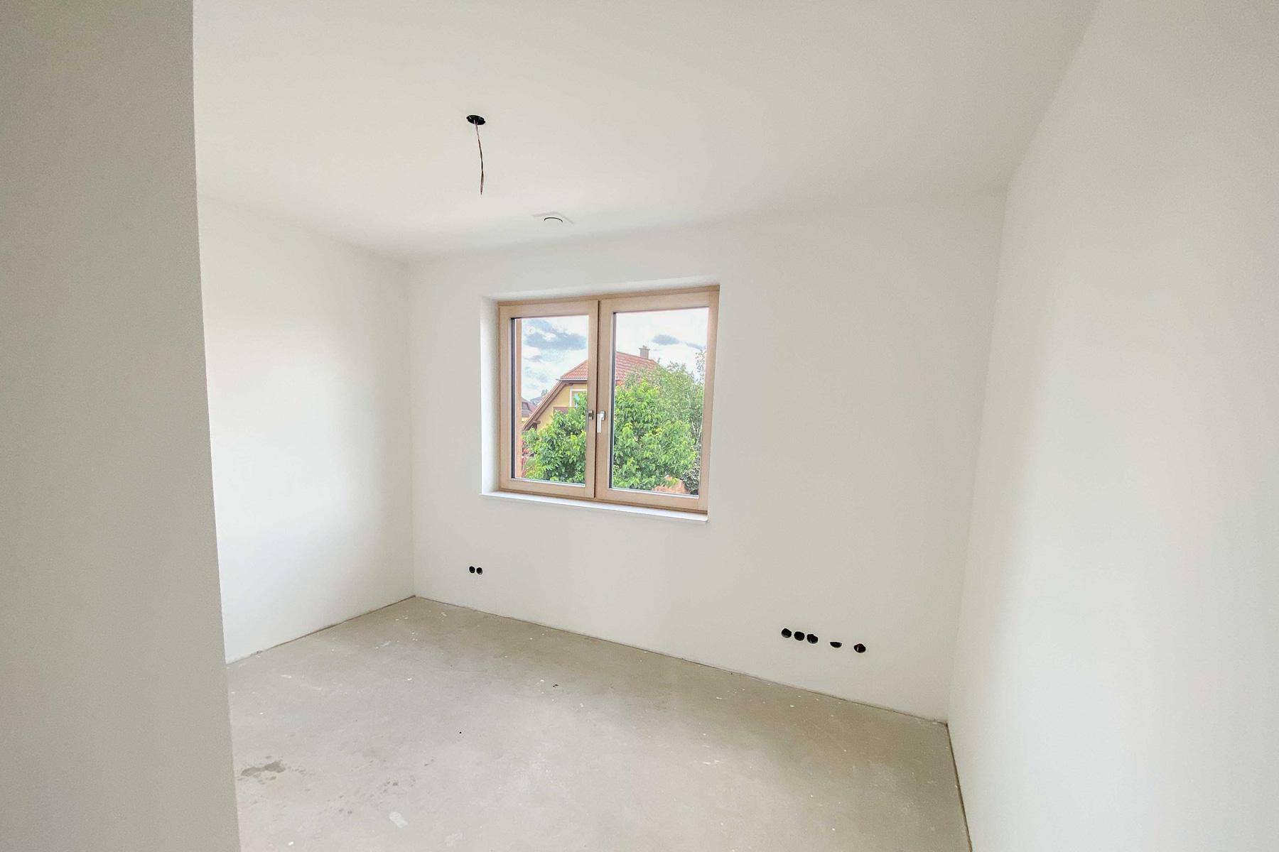 Unmöblierter Raum in einem Neubau mit Fenster und Blick ins Grüne.