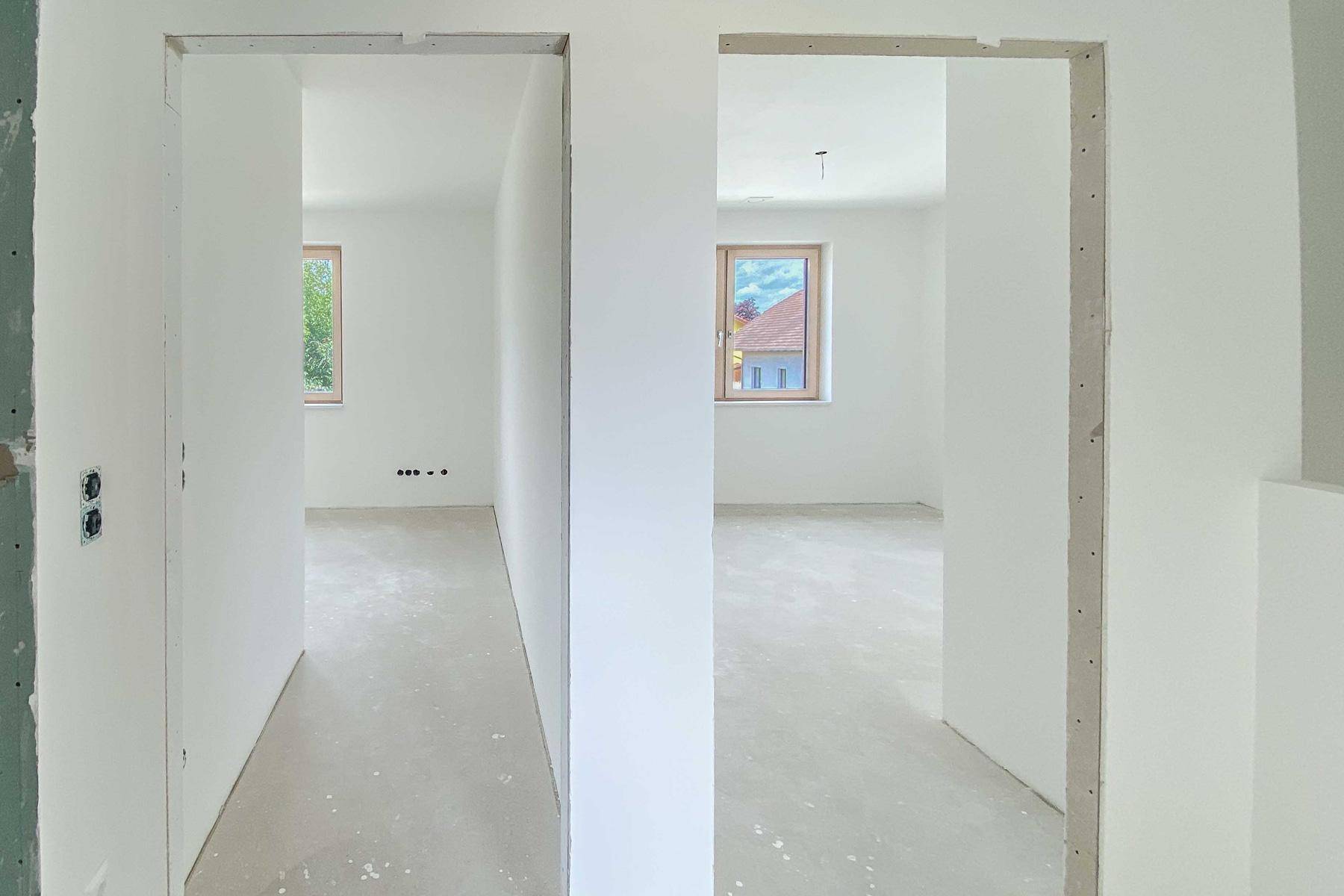 Heller Flur mit Durchgängen zu weiteren unmöblierten Räumen in einem Neubau.