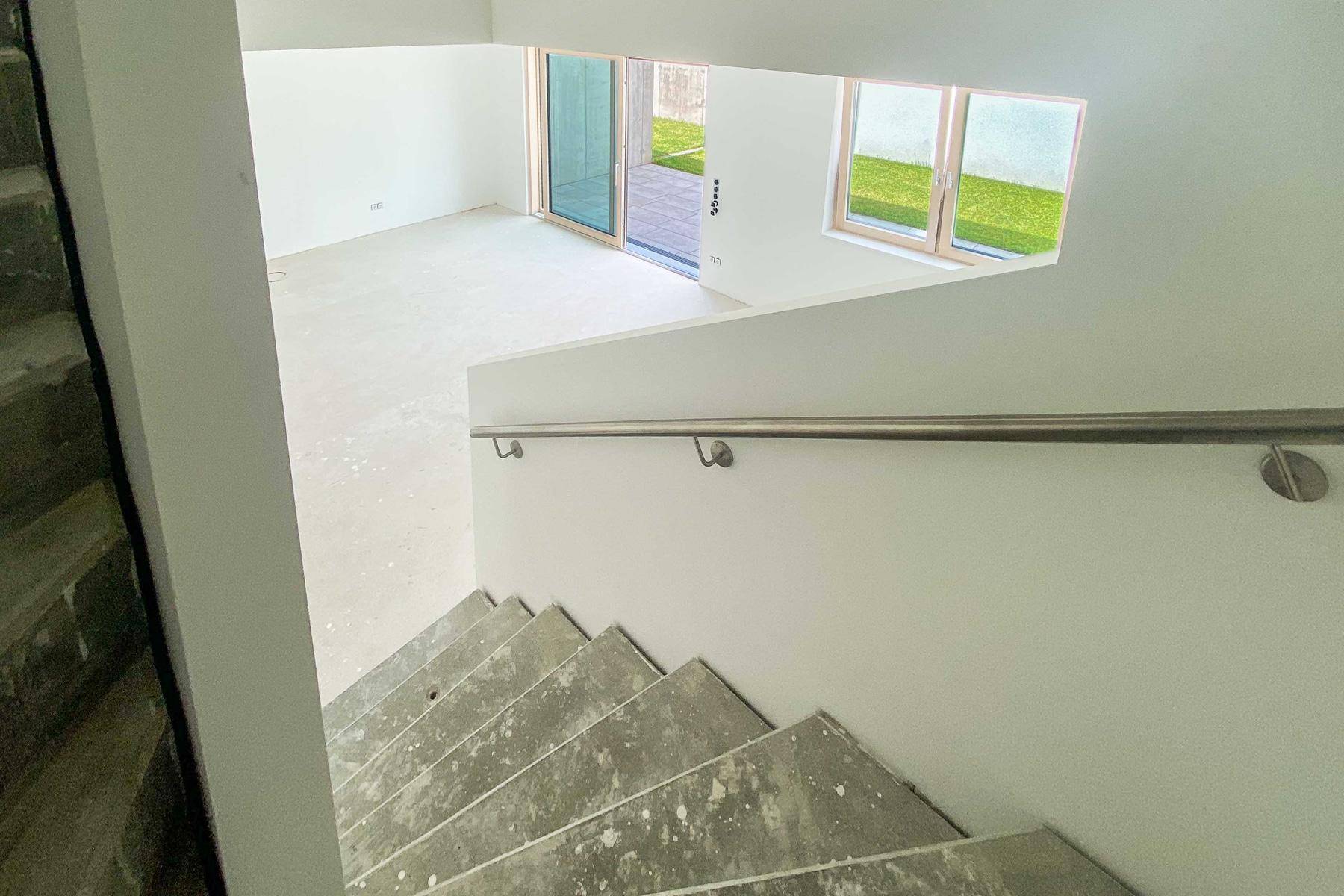 Blick von der Treppe hinunter in den hellen Wohnbereich mit Gartenzugang.