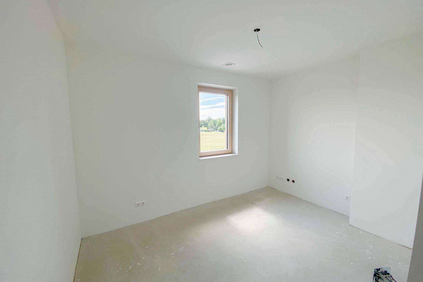 Helles, unfertiges Schlafzimmer mit weitem Ausblick durch das Fenster.
