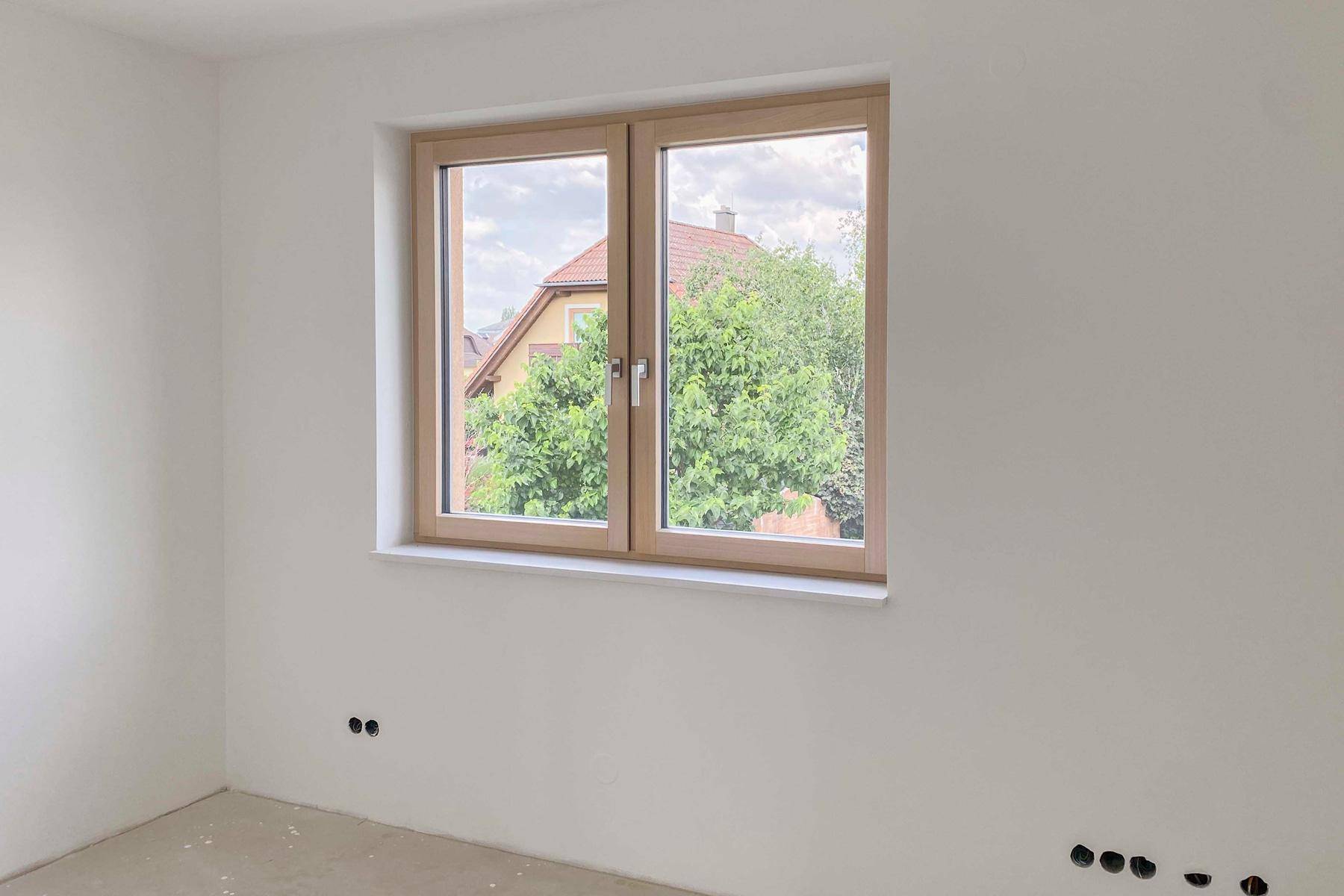 Unfertiges Schlafzimmer mit Fenster und Ausblick auf die Nachbarschaft.