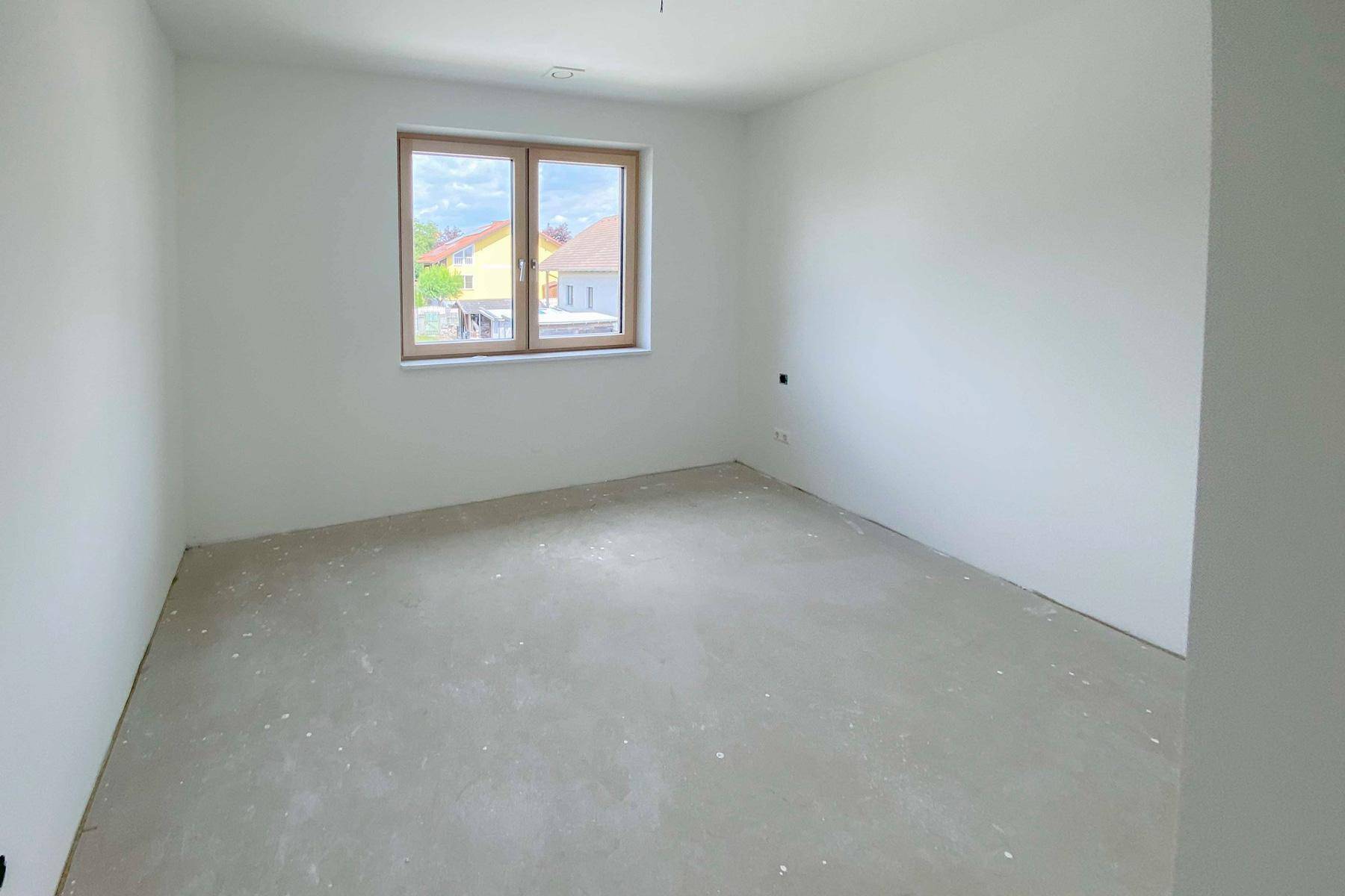 Unfertiges Schlafzimmer mit Fenster und Blick auf die benachbarten Gebäude.