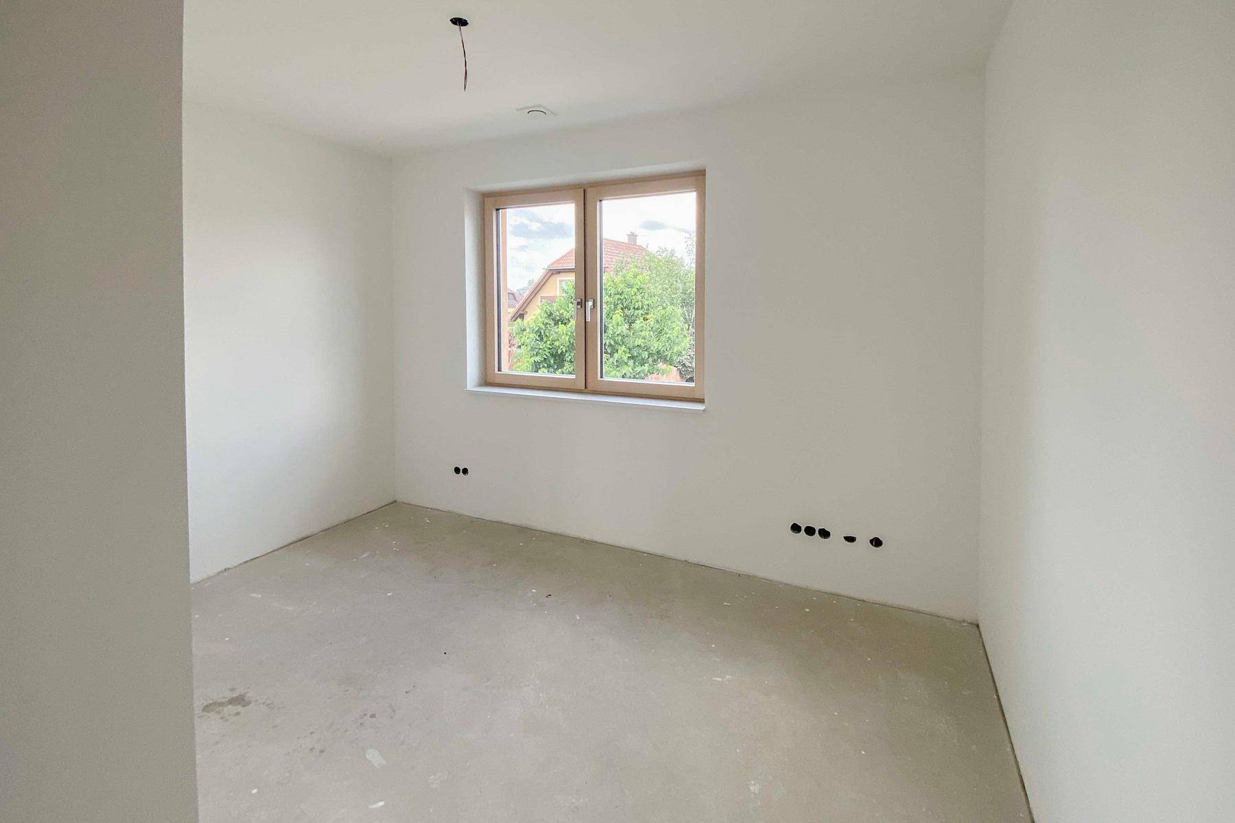 Unfertiges Schlafzimmer mit Fenster und Blick auf die umliegenden Häuser.