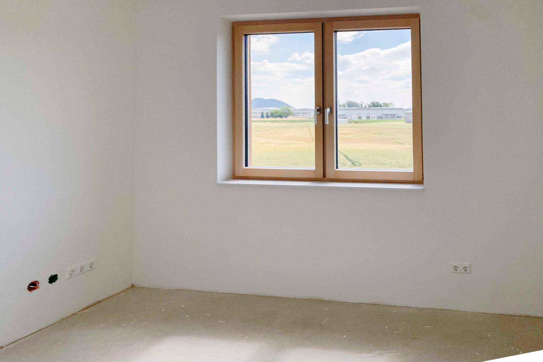 Helles, unfertiges Schlafzimmer mit weitem Blick über Felder und Landschaft.