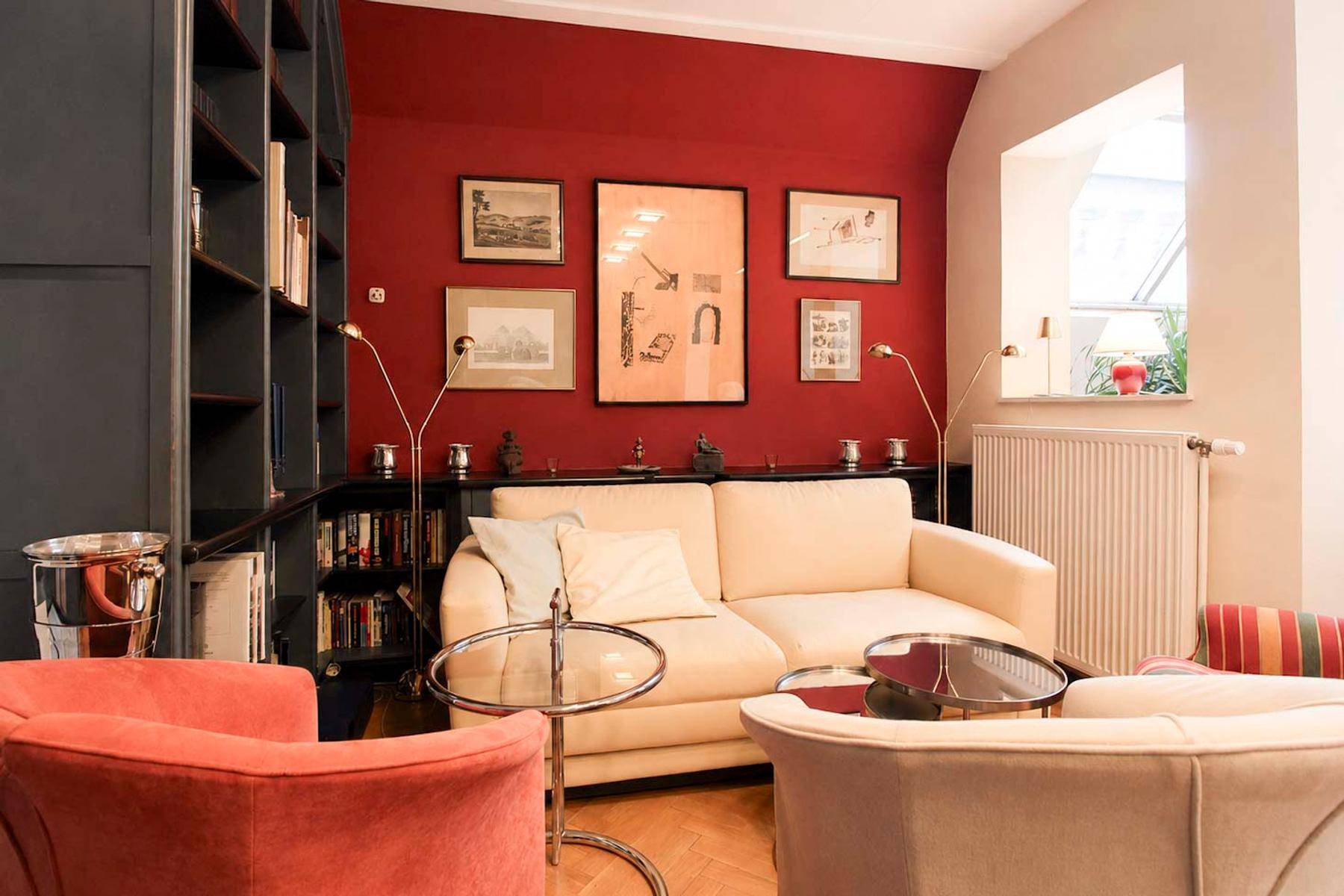 Gemütliches Wohnzimmer mit roter Akzentwand, Bücherregalen und bequemen Sitzmöbeln für Lesestunden.