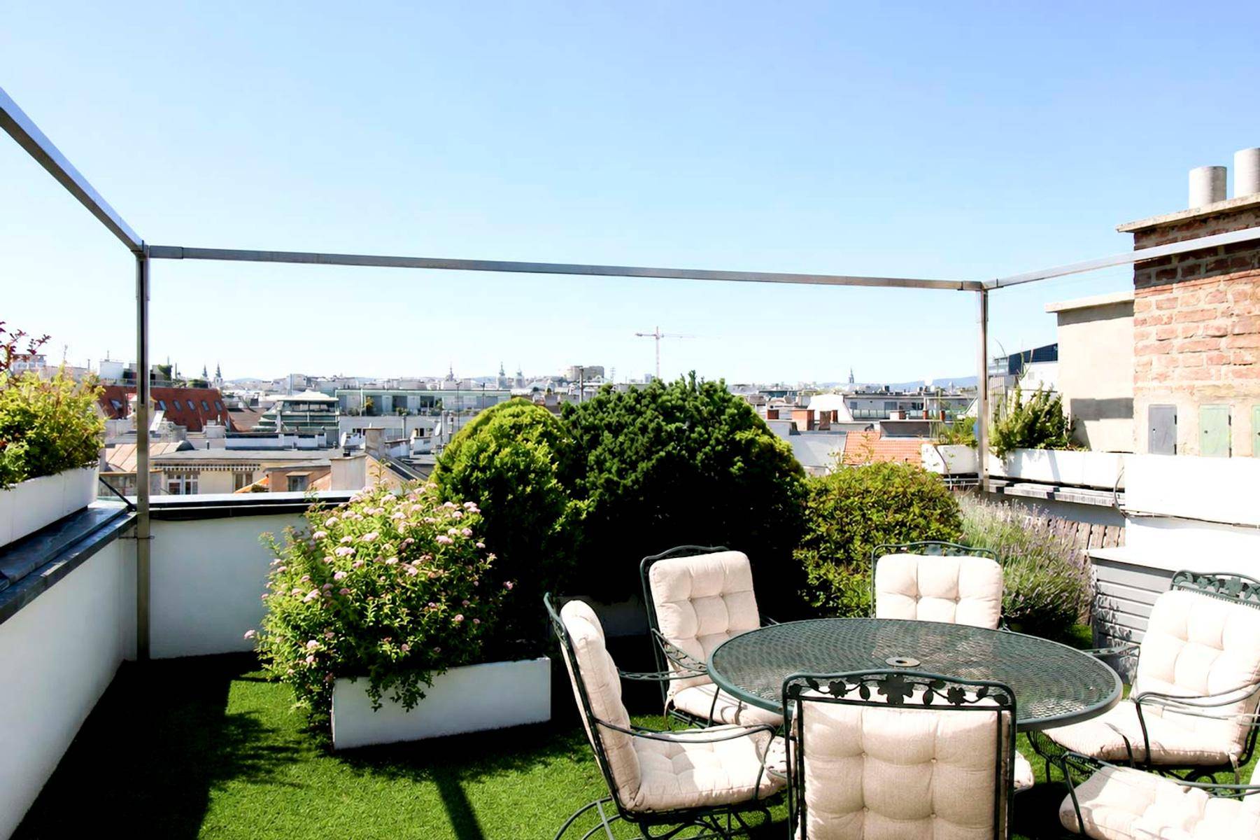 Geräumige Dachterrasse mit Gartenmöbeln, Pflanzen und weitem Blick über die Stadtlandschaft.
