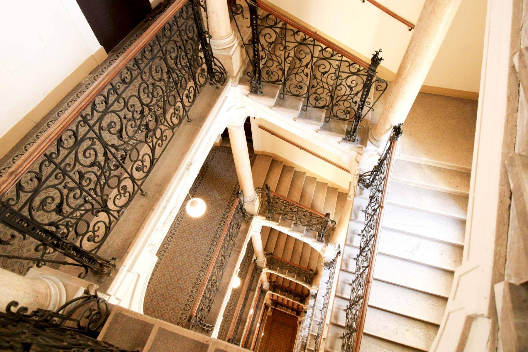 Historisches Treppenhaus mit kunstvollen schmiedeeisernen Geländern und eleganten Steinstufen.