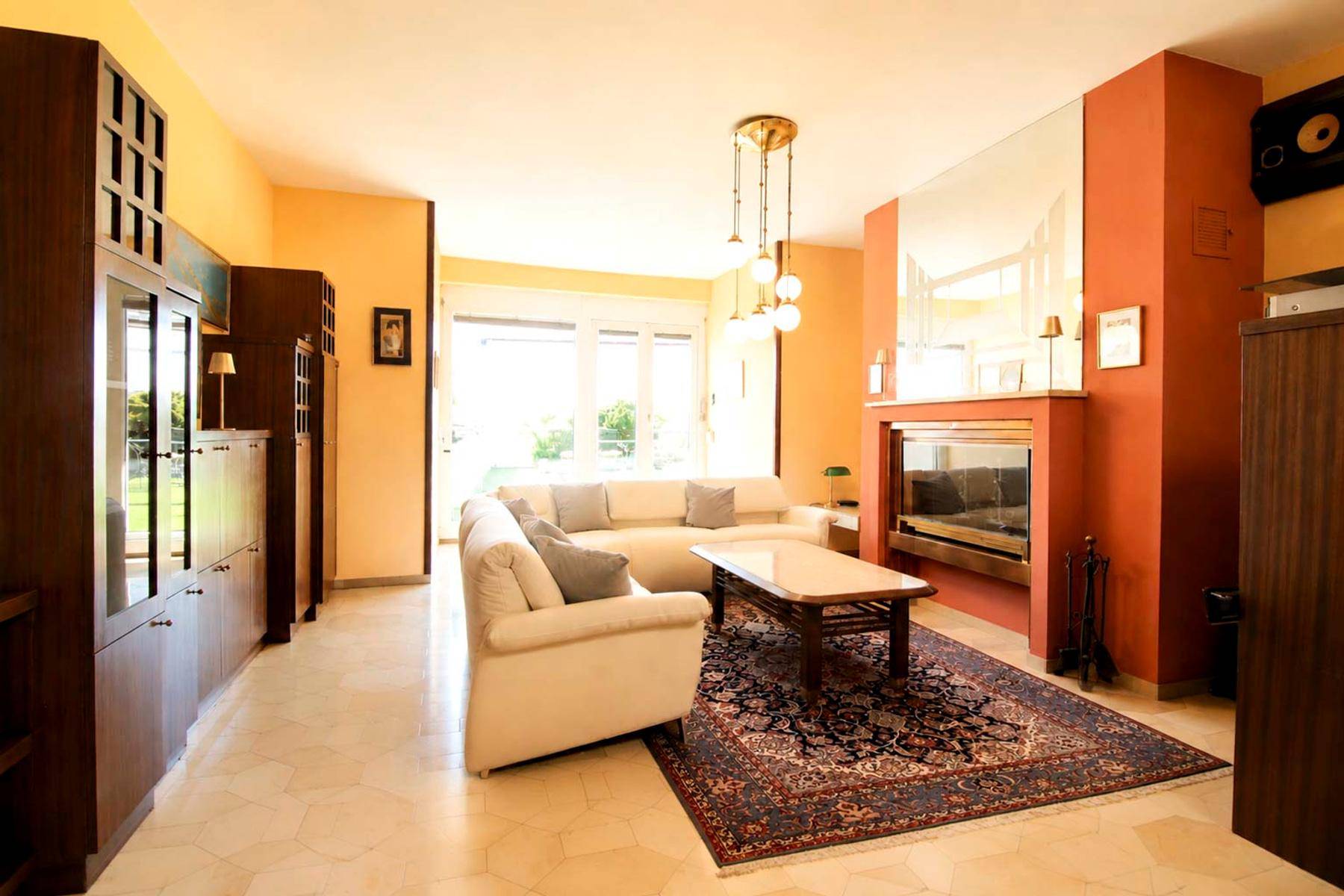 Helles Wohnzimmer mit Kamin, beigefarbenem Sofa und eleganten Holzschränken, ideal zum Entspannen.