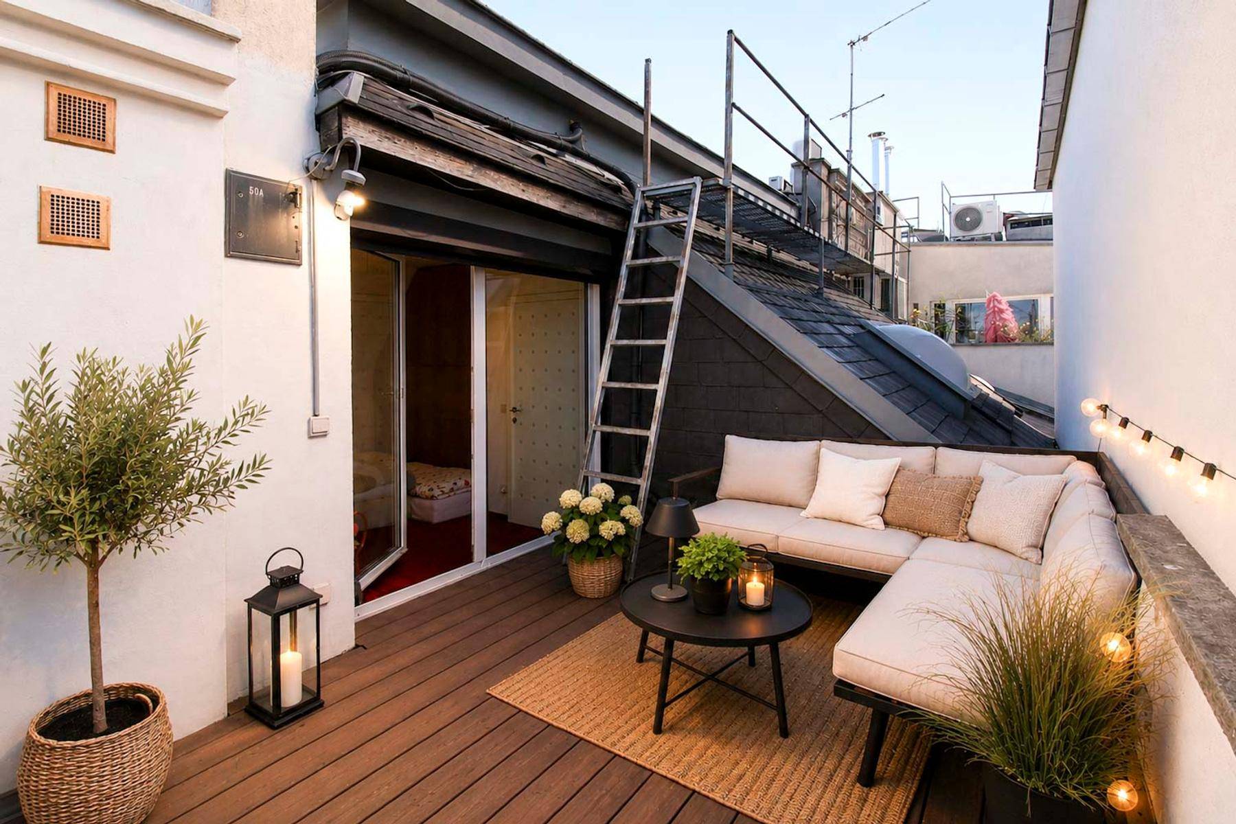 Gemütliche Terrasse mit Holzdeck, Lounge-Sofa und stimmungsvoller Lichterkette für Abendstunden.