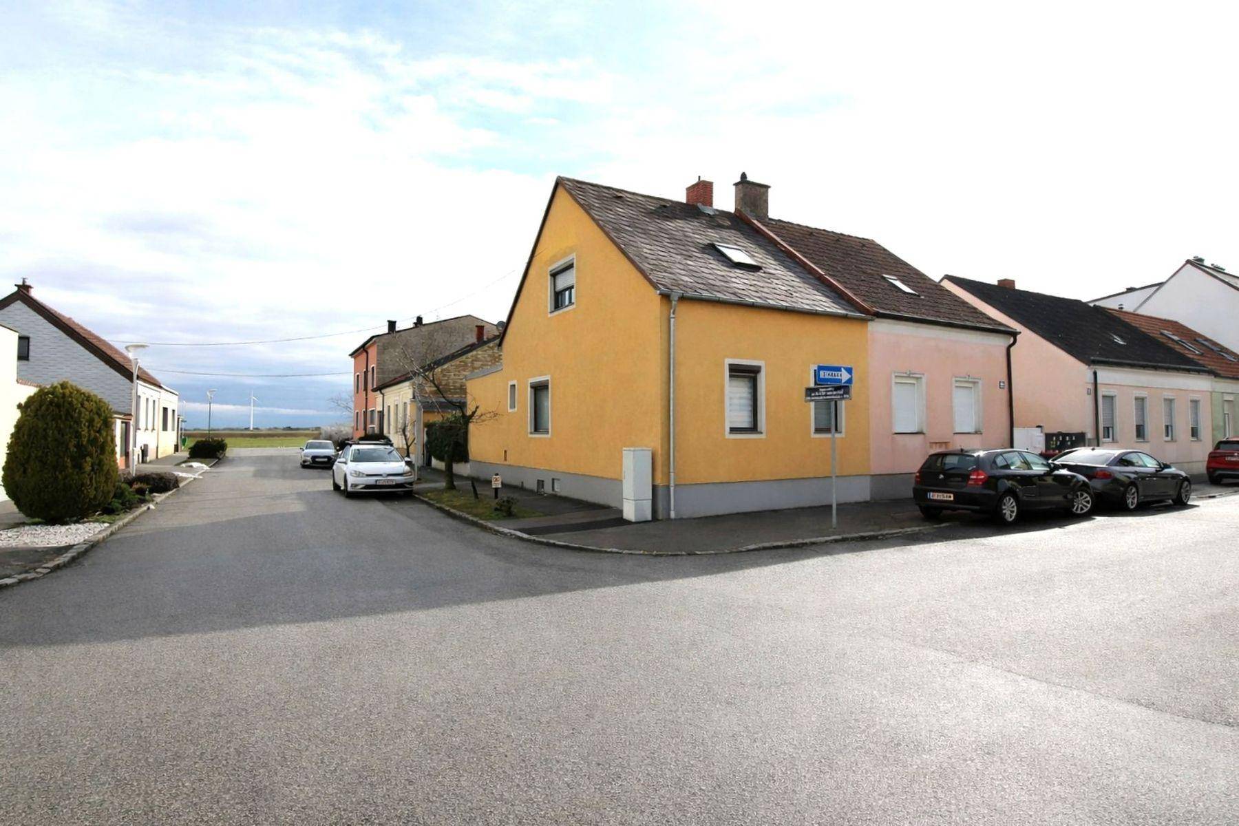 Ansicht des Hauses von der Straße mit umliegenden Gebäuden und parkenden Autos.