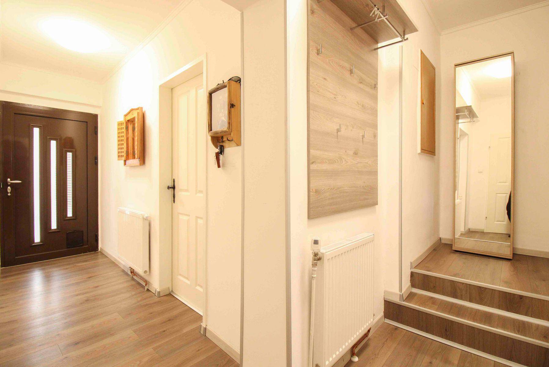 Heller Flur mit Garderobe, Eingangstür und Treppenaufgang zu den oberen Etagen.