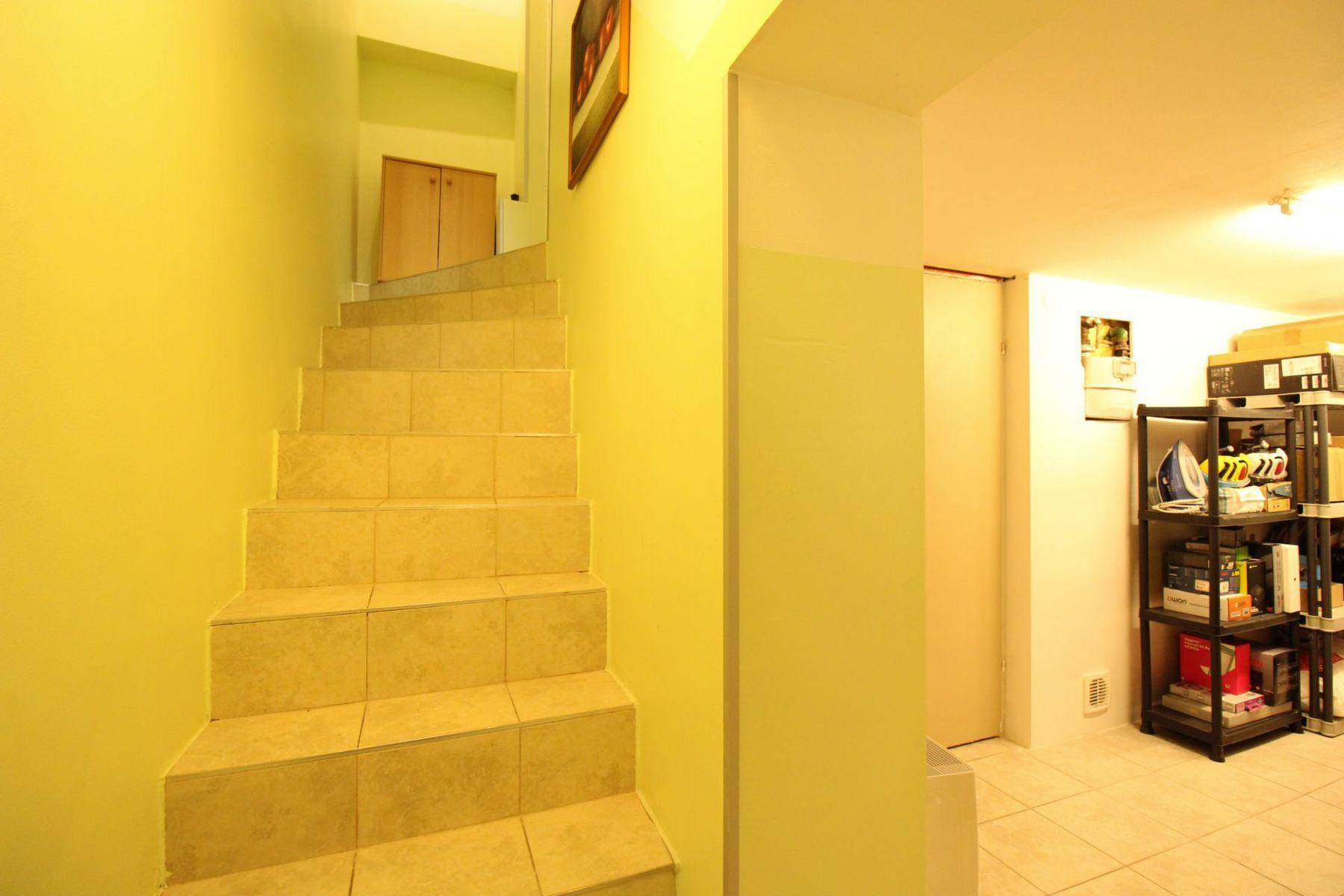 Geflieste Treppe führt hinunter in den Kellerbereich mit angrenzendem Abstellraum.