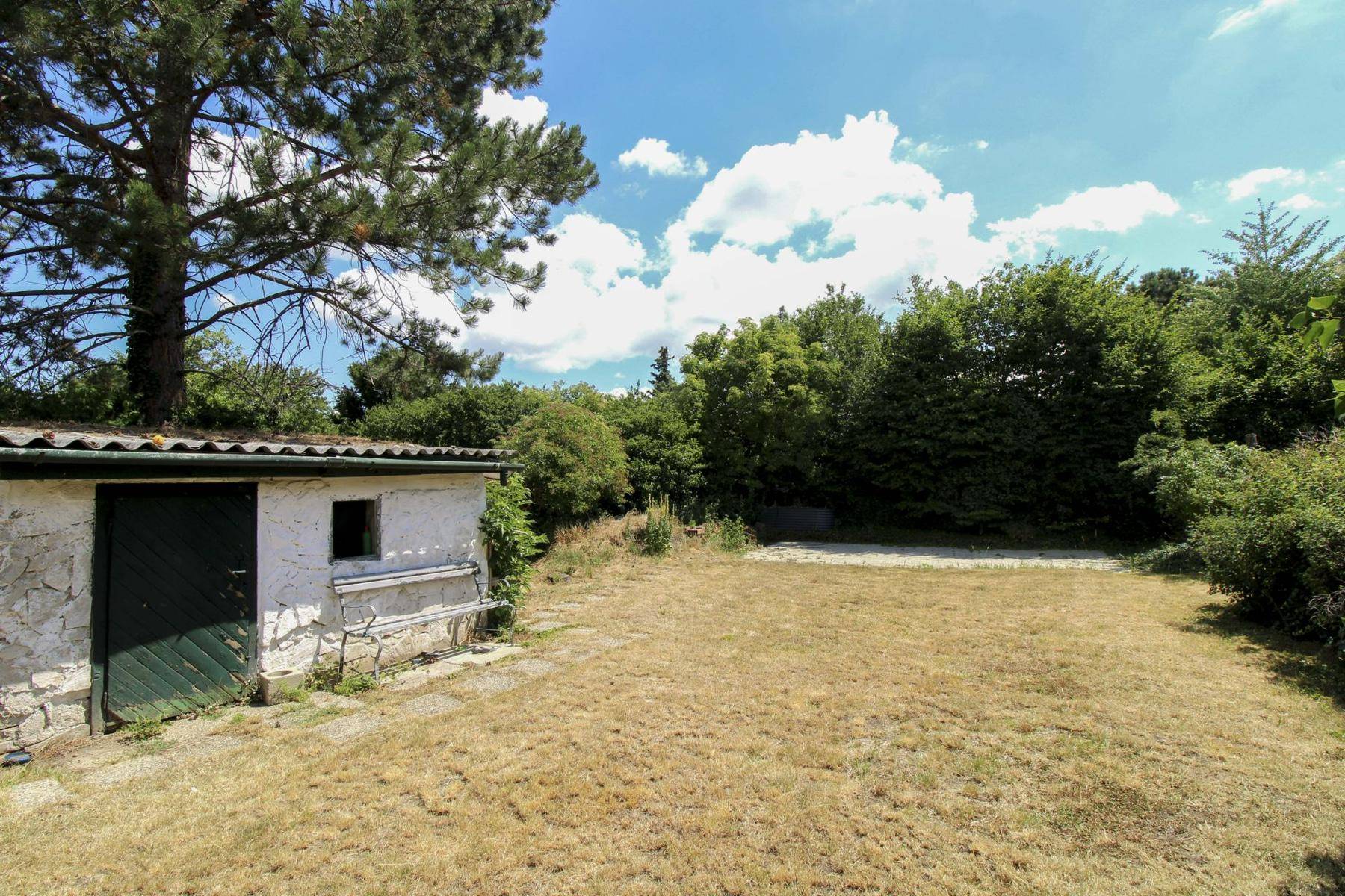 Weiterer Blick in den weitläufigen Garten mit Schuppen und viel Grün.