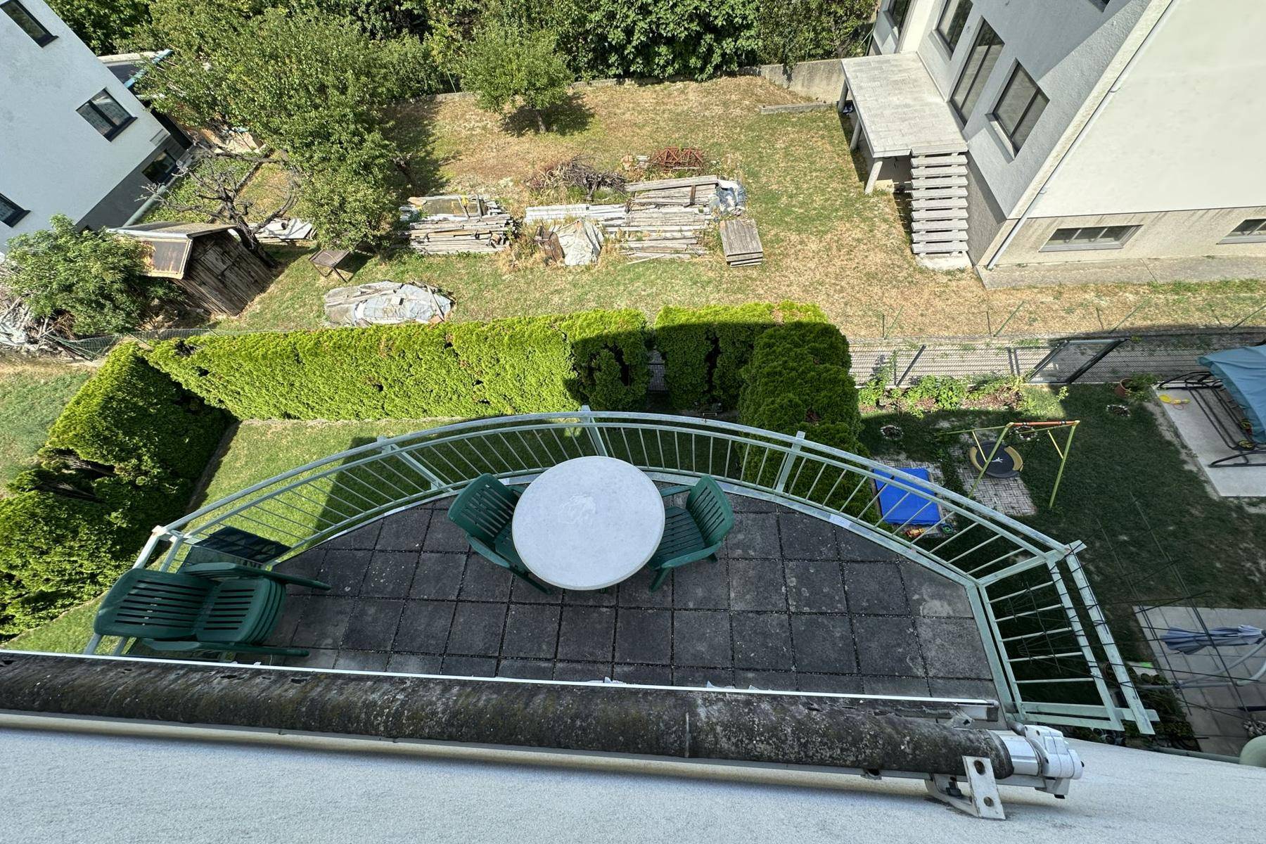 Balkon mit Sitzgelegenheiten und Blick auf den grünen Gartenbereich und die umliegenden Gebäude.