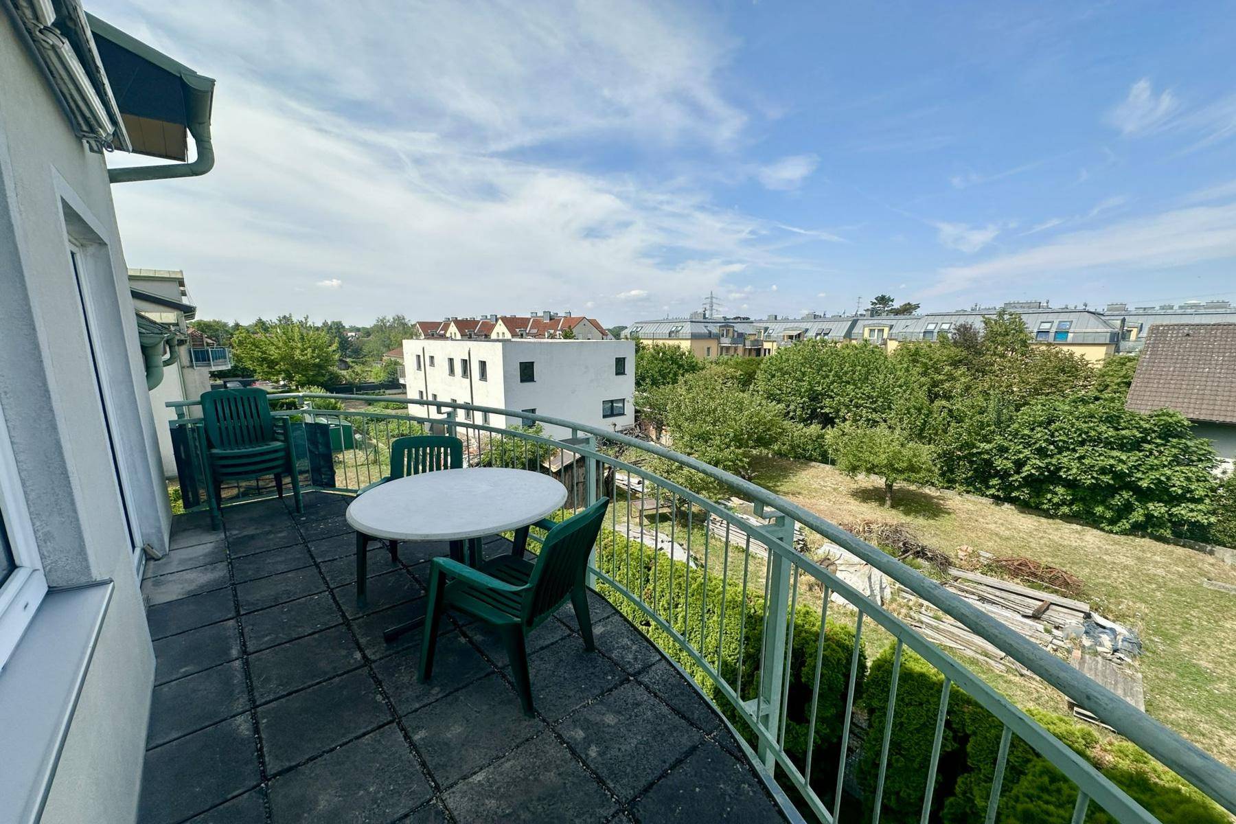 Geräumiger Balkon mit Gartenmöbeln und weitem Blick über die grüne Umgebung und Nachbarschaft.