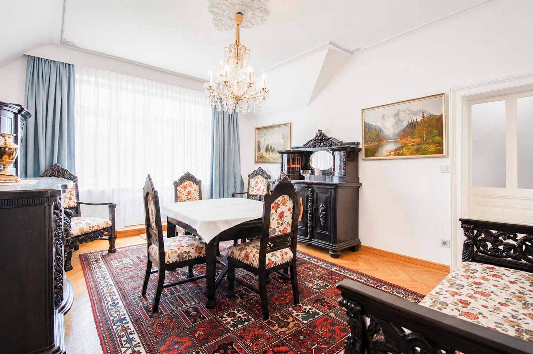 Klassisches Esszimmer mit antiken Möbeln, Kronleuchter und gemustertem Teppich.