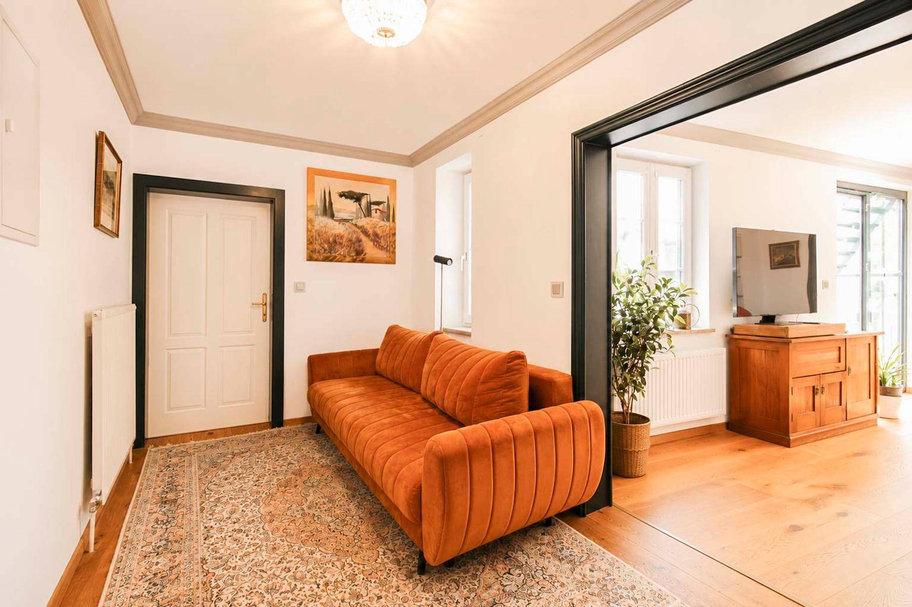 Heller Eingangsbereich mit bequemer Couch und offenem Übergang zum Wohnbereich.