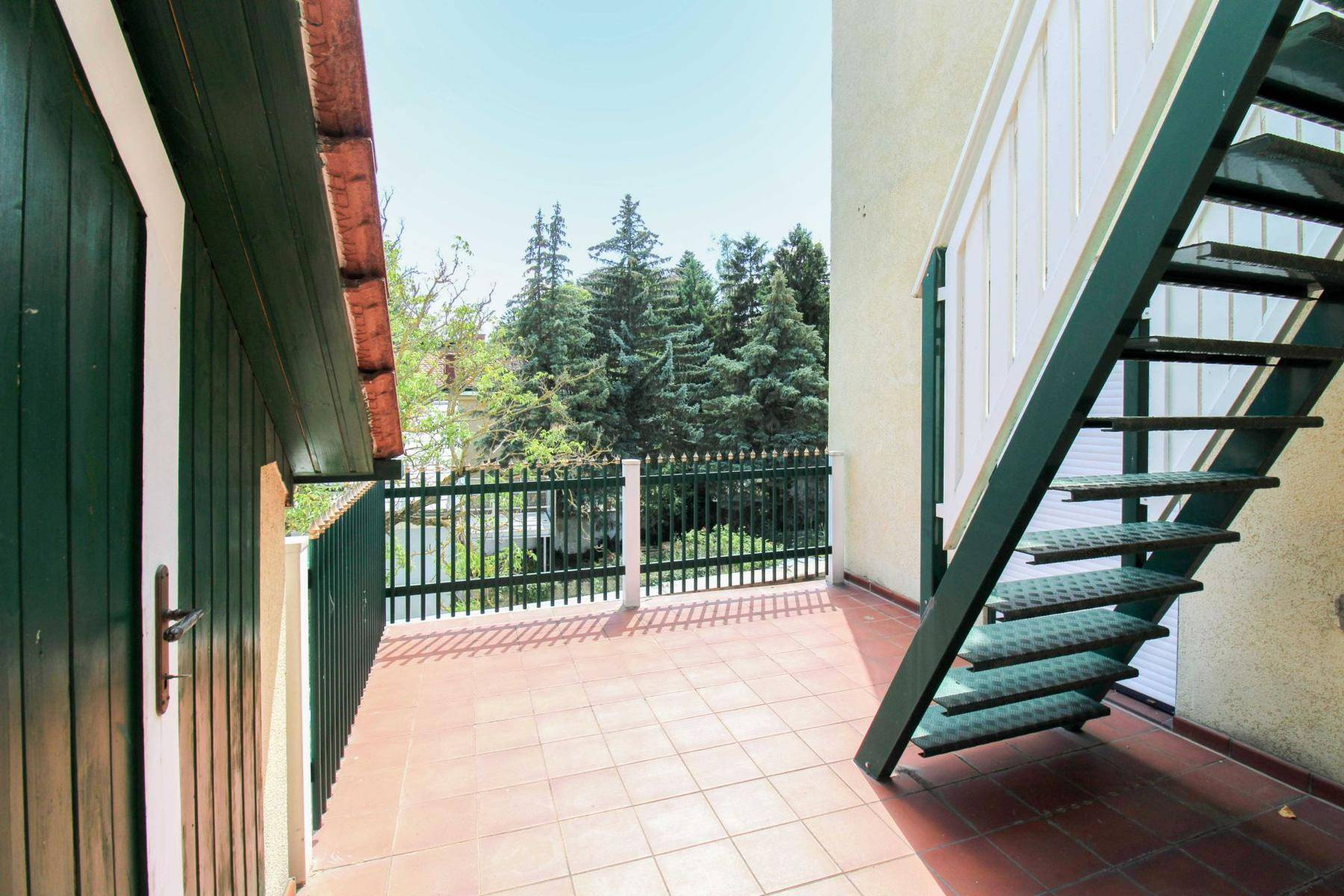 Geflieste Terrasse mit Außentreppe und einem schönen Blick ins Grüne.