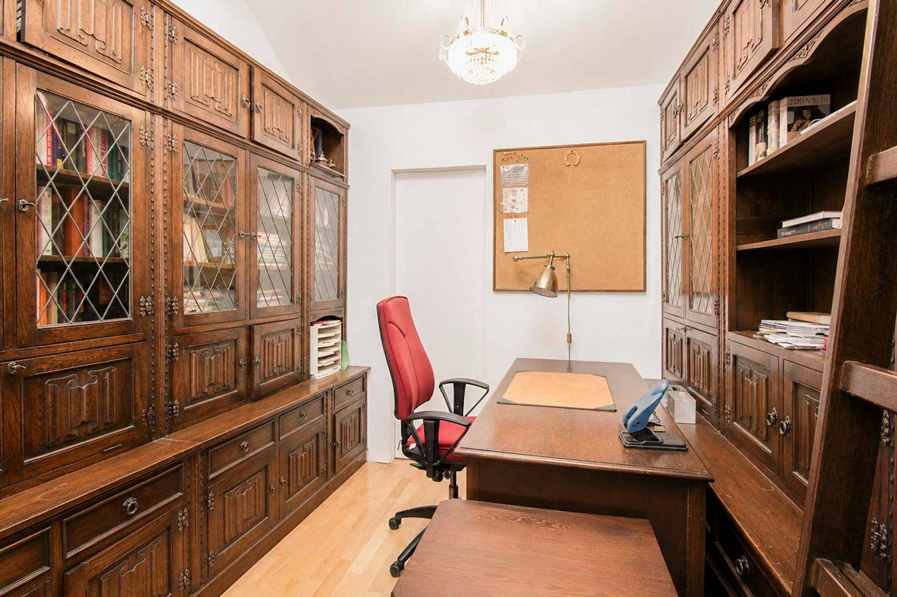 Elegantes Arbeitszimmer mit dunklen Holzschränken, großem Schreibtisch und viel Stauraum.
