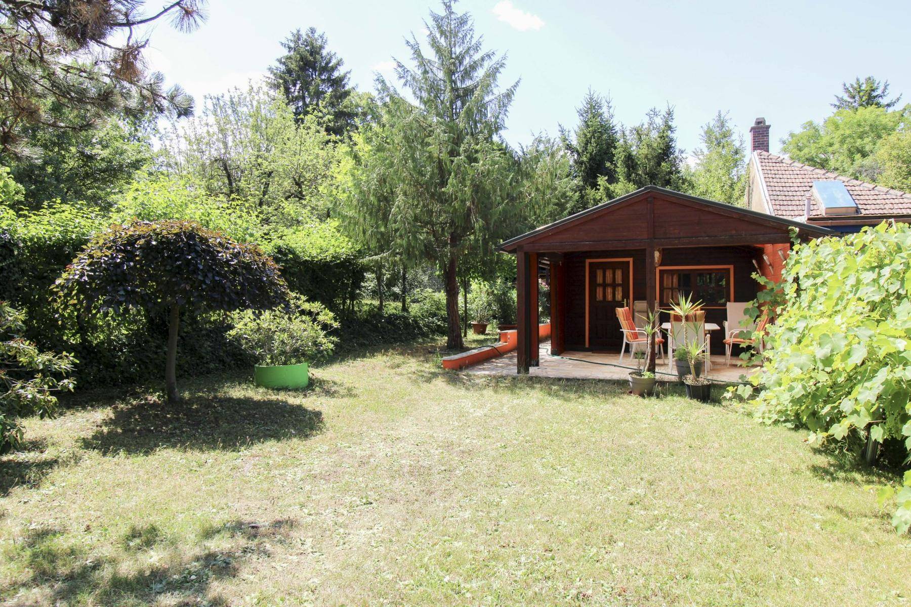 Großer Garten mit Rasenfläche, Bäumen und einer überdachten Terrasse für gemütliche Stunden.